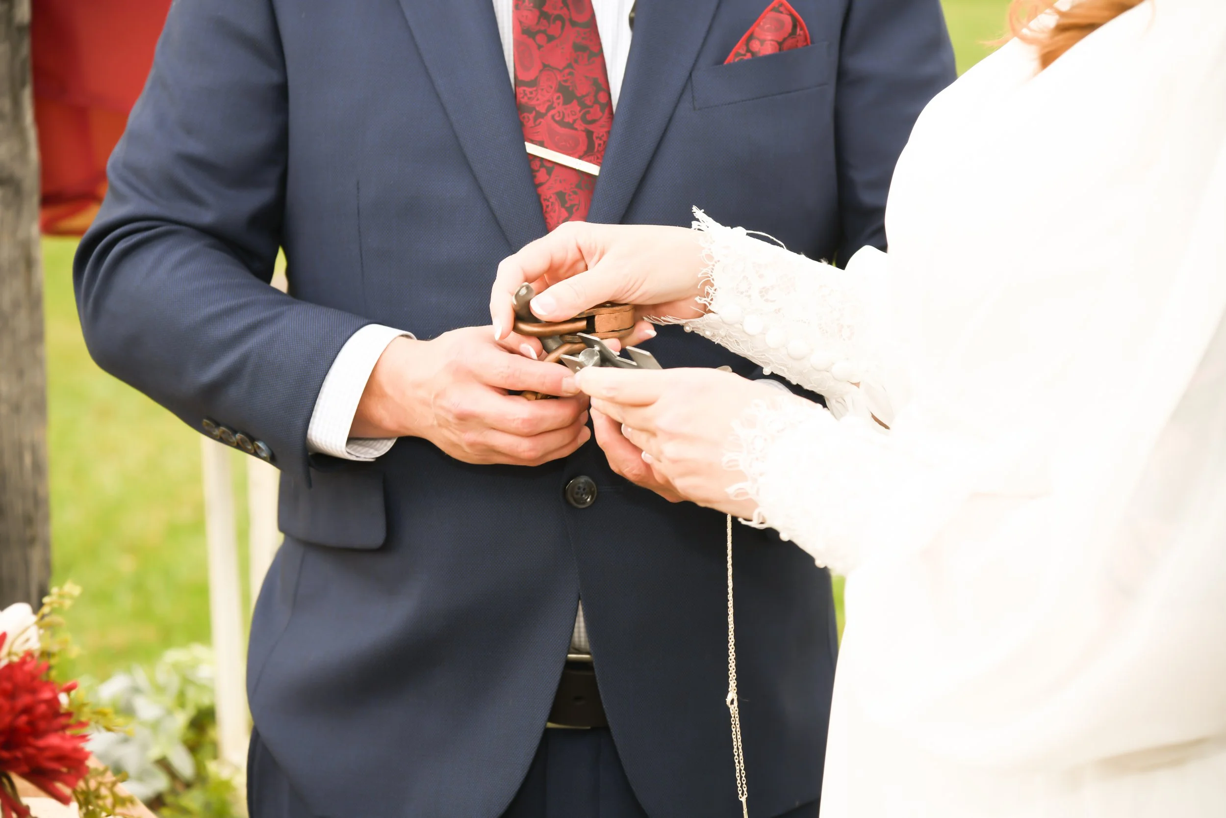 A groom and bride exchanging rings during a wedding ceremony outdoors.
