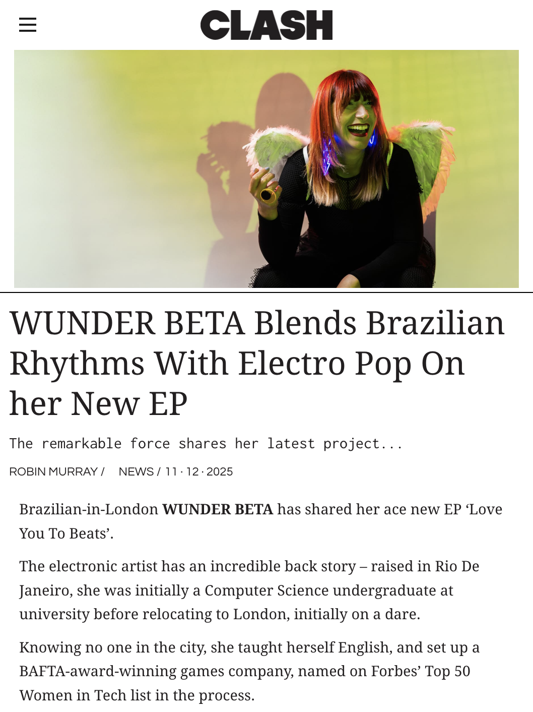 WUNDER BETA (Roberta Lucca) featured on CLASH Magazine, wearing angel wings and neon earrings, smiling and laughing. She is sitting against a green background with a shadow cast behind her.