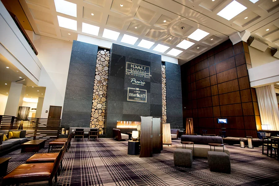 Hotel lobby with modern decor, wooden accents, comfortable seating, and large ceiling lights.
