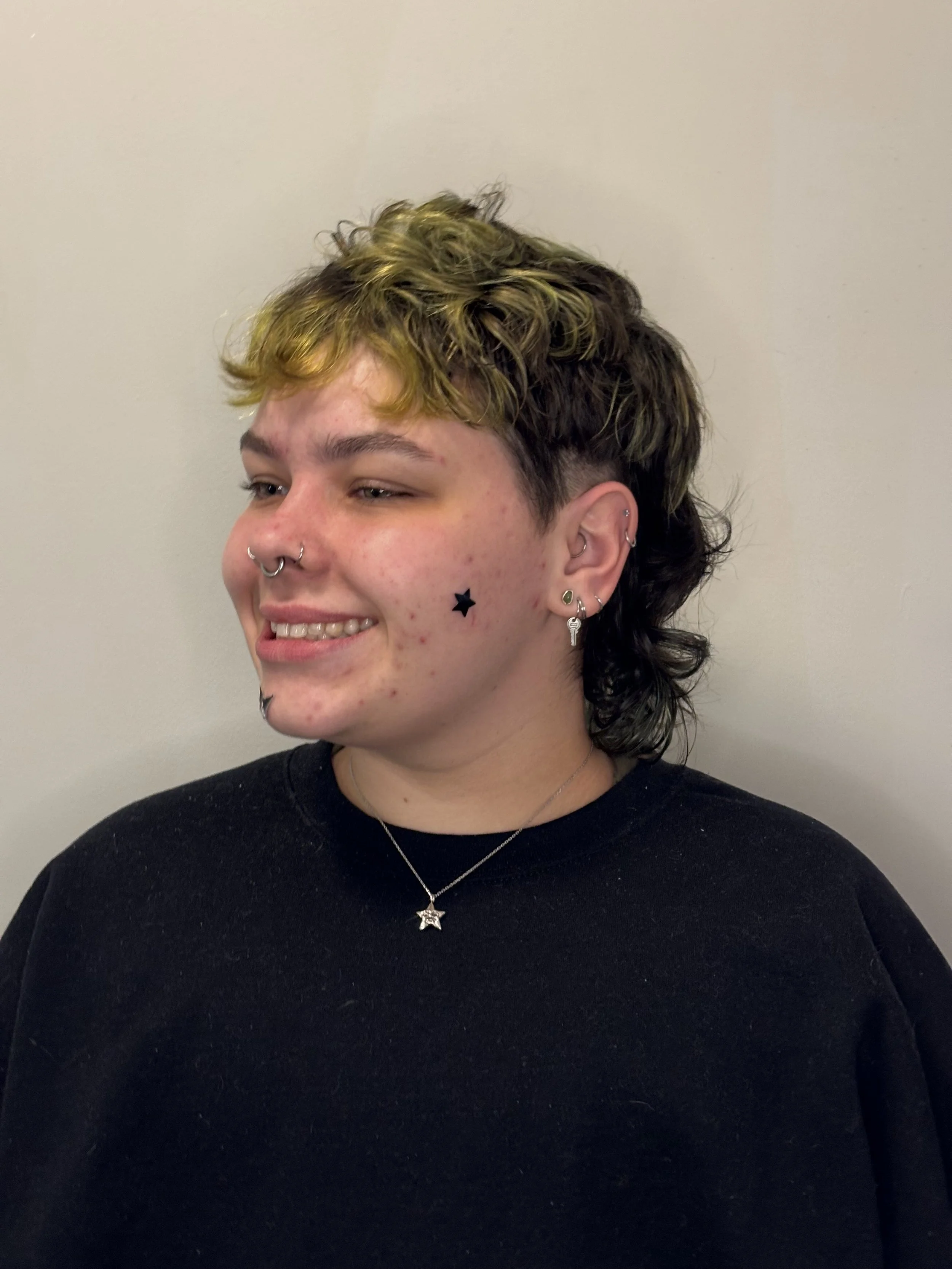 Short, curly, two-tone hair with blonde on top and dark underneath.