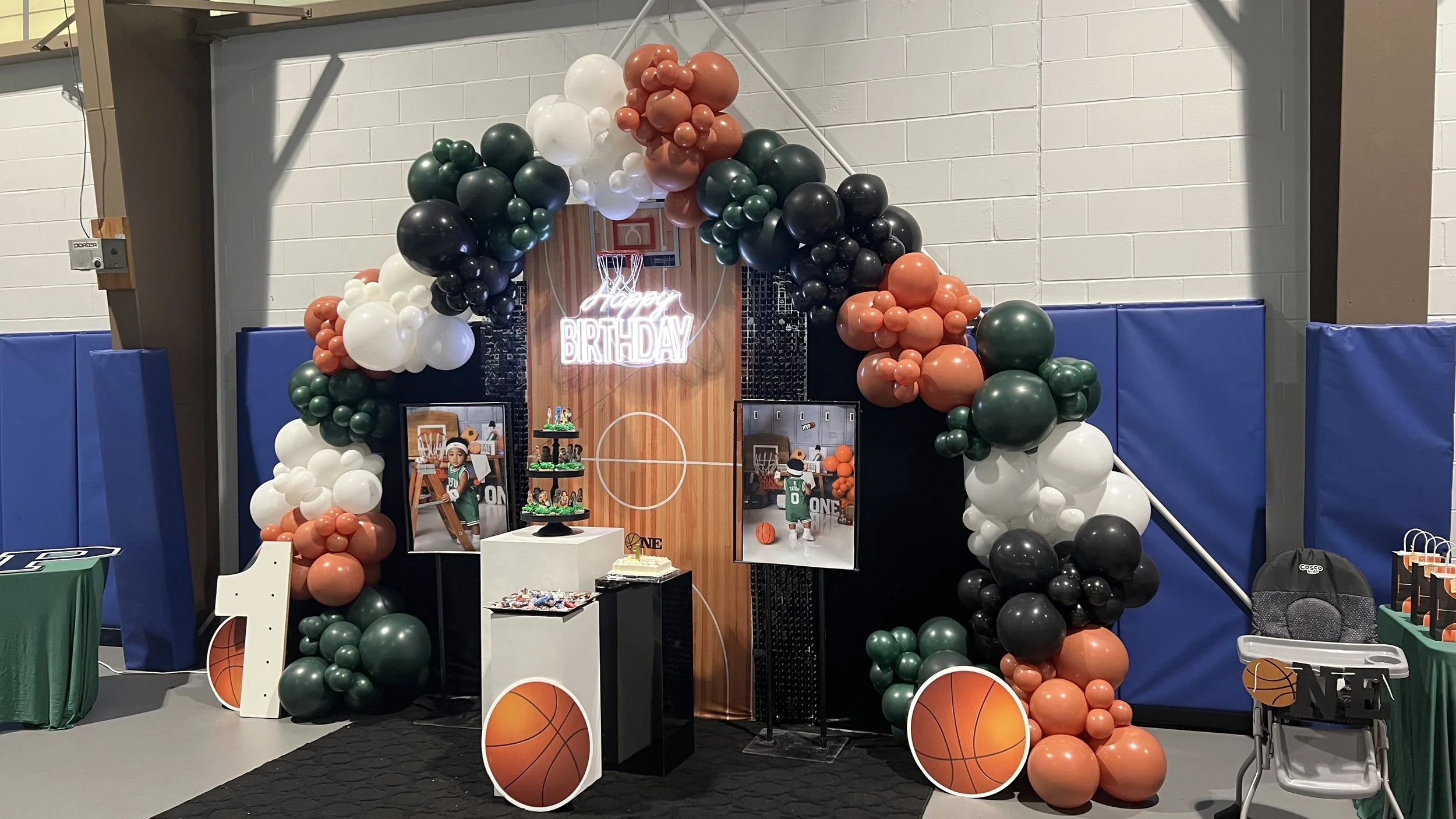 Basketball-themed birthday party decoration with balloon arch, birthday sign, and basketball images.