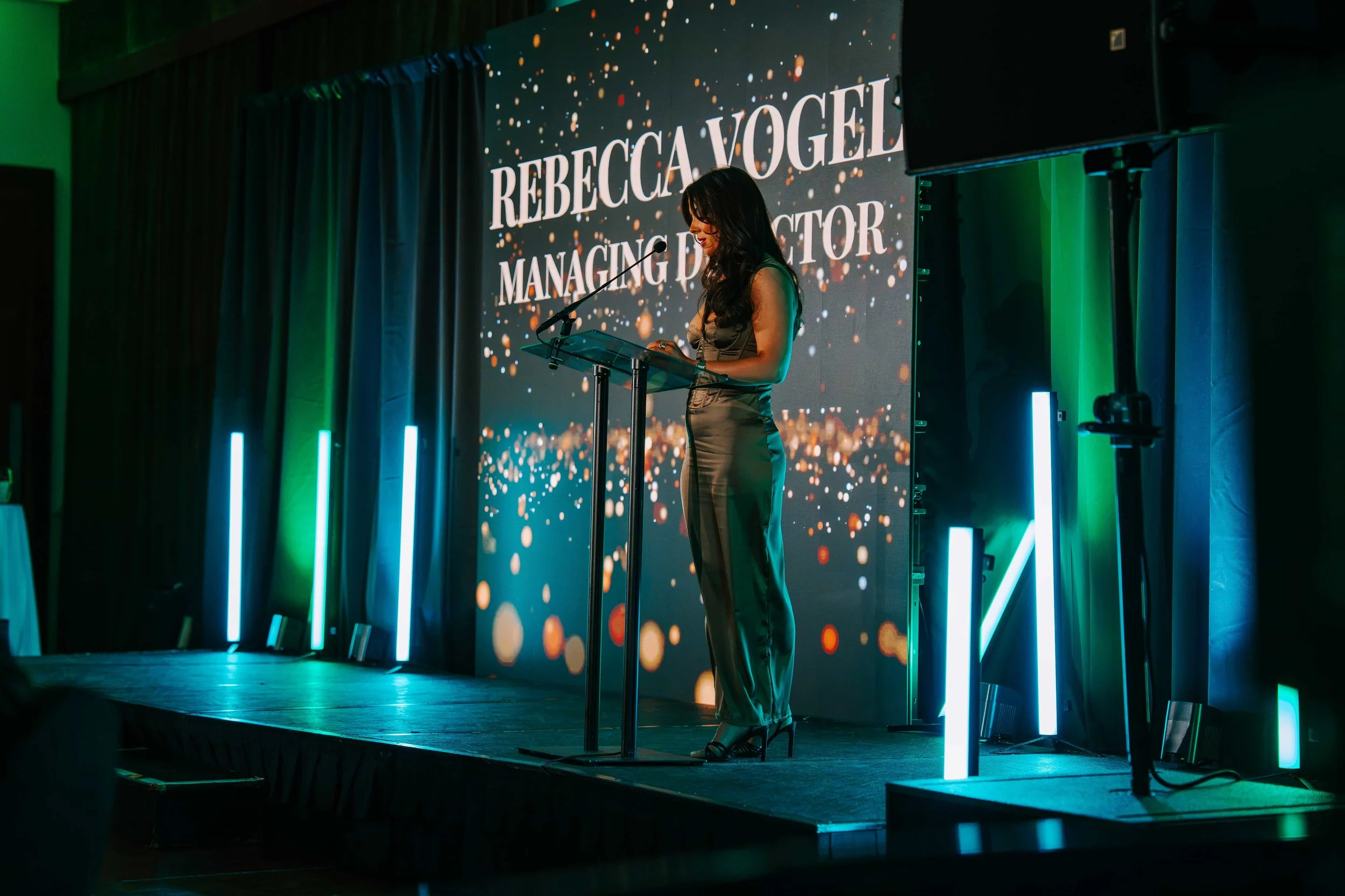 Connected Health Managing Director Rebecca Vogel speaking at the lectern, with her name and title on the LED wall