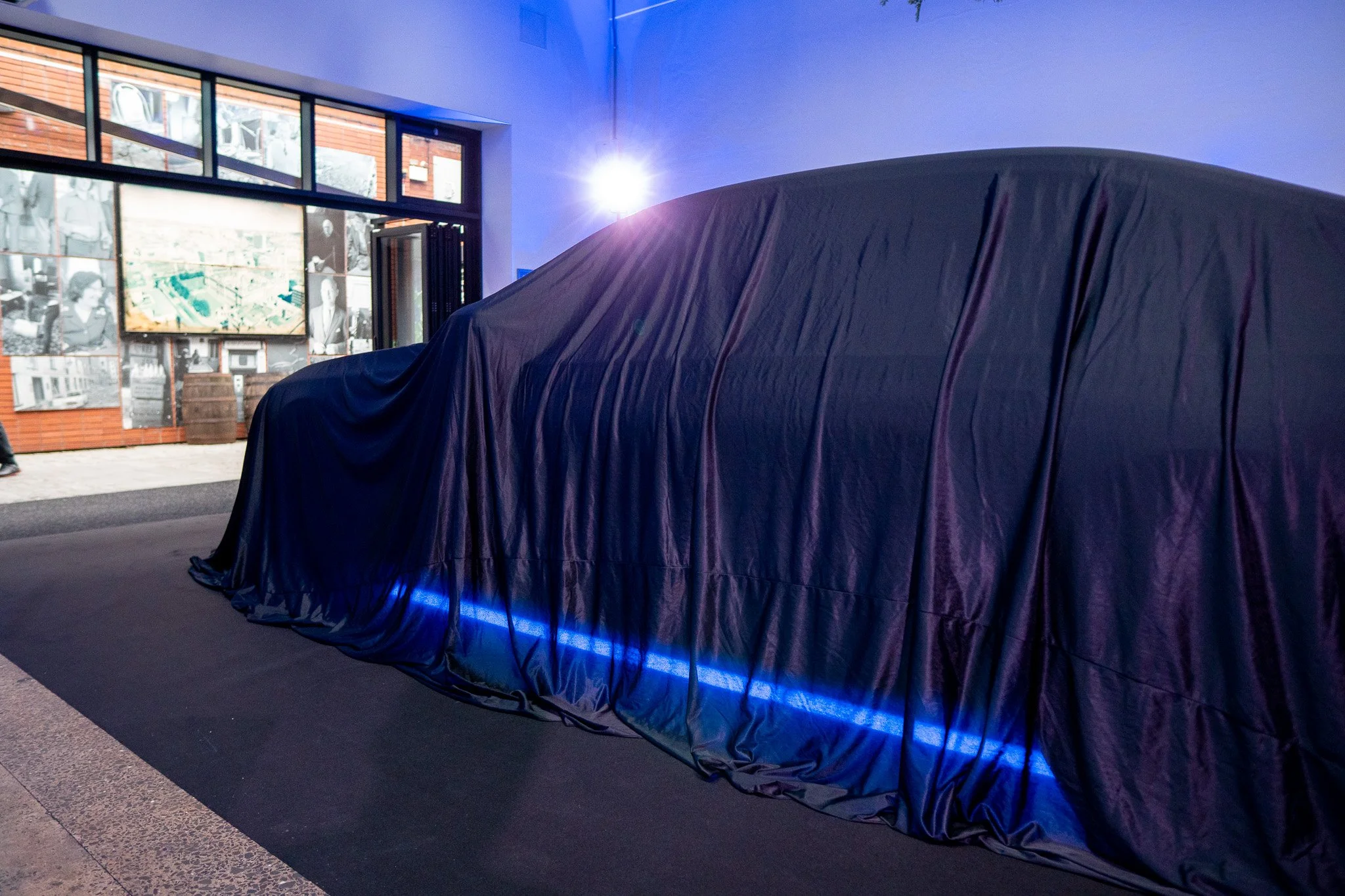 BMW i7 under cover at the centre of Waterman House ahead of the reveal, with LED Fresnels set at the front corners