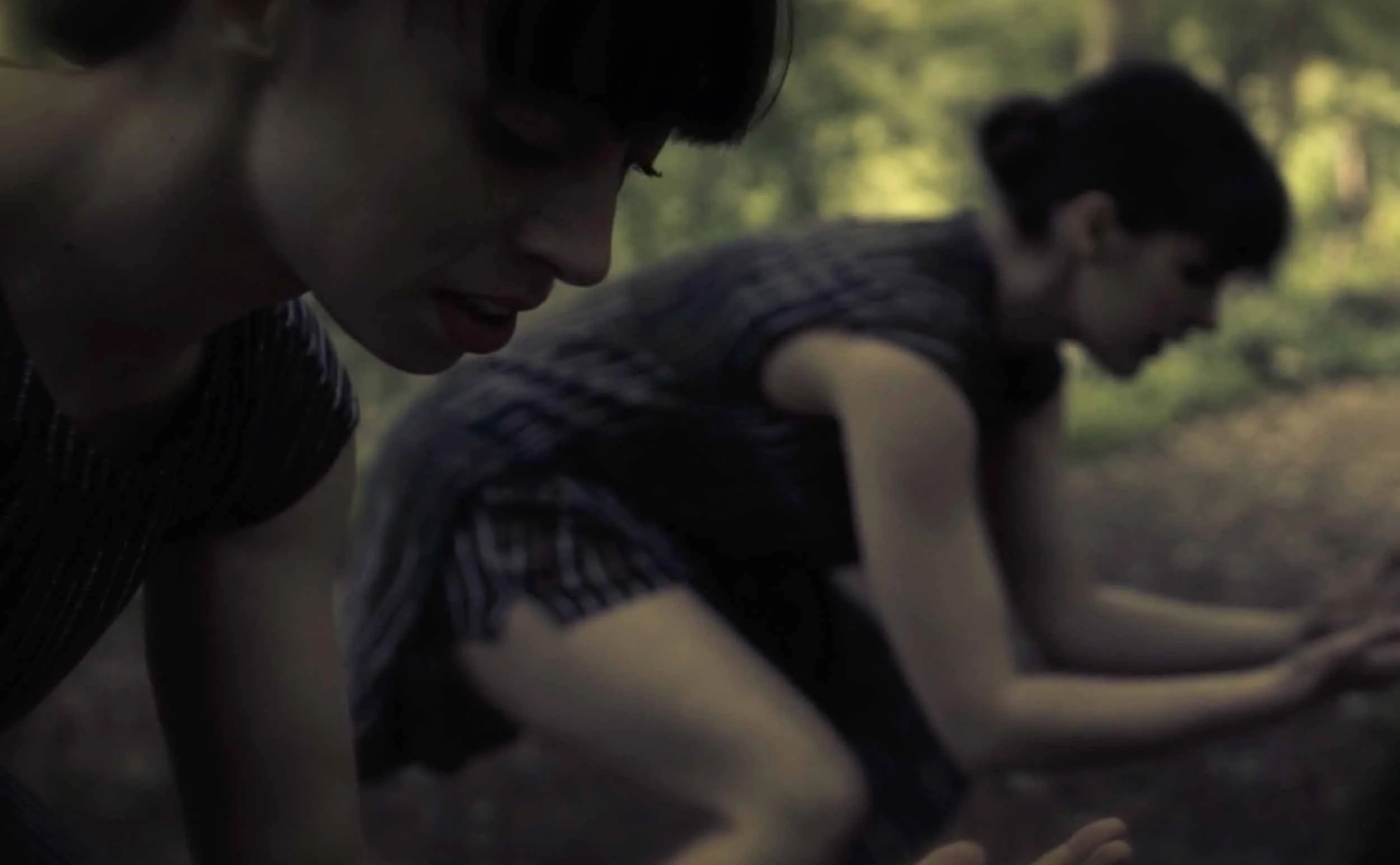 Two female dancers crouching low in the woods.