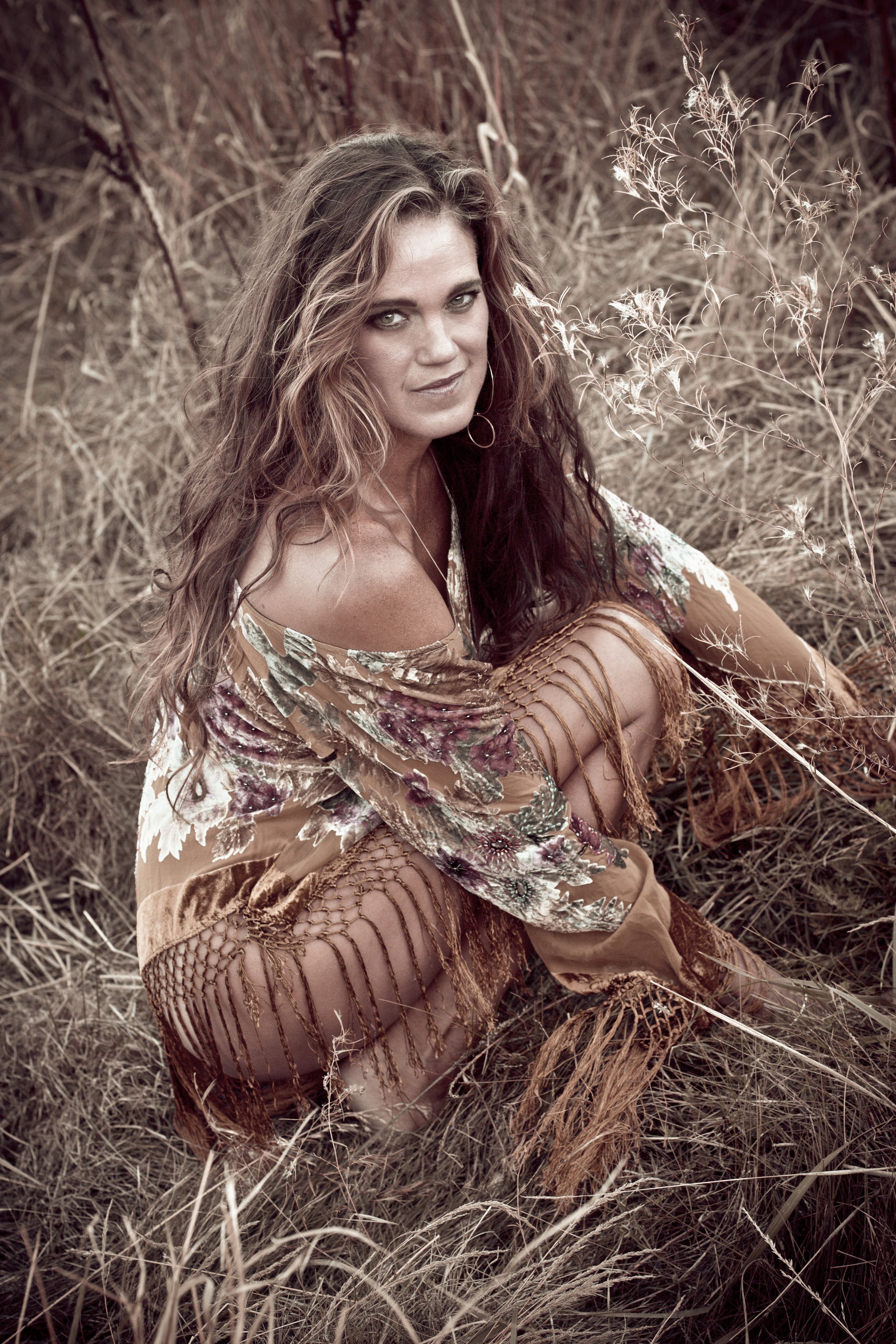 Woman crouching in a field wearing a floral shawl