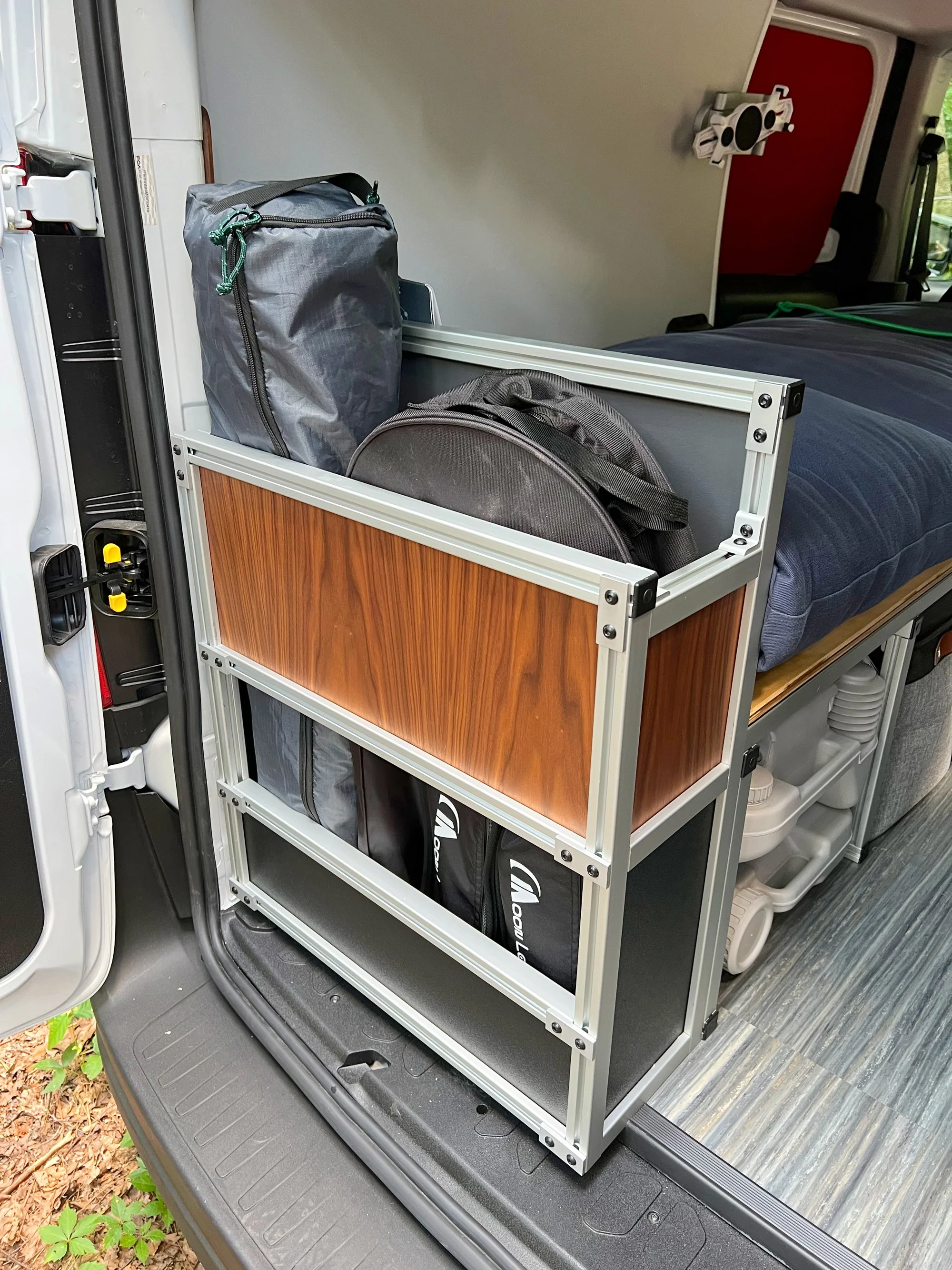 The rear stowage locker is multi-functional. The interior floor shelf can be removed to store taller items. The Moon Shade awning, two camping chairs, a foldable table and the 50 ft shore power cable all fit as shown!