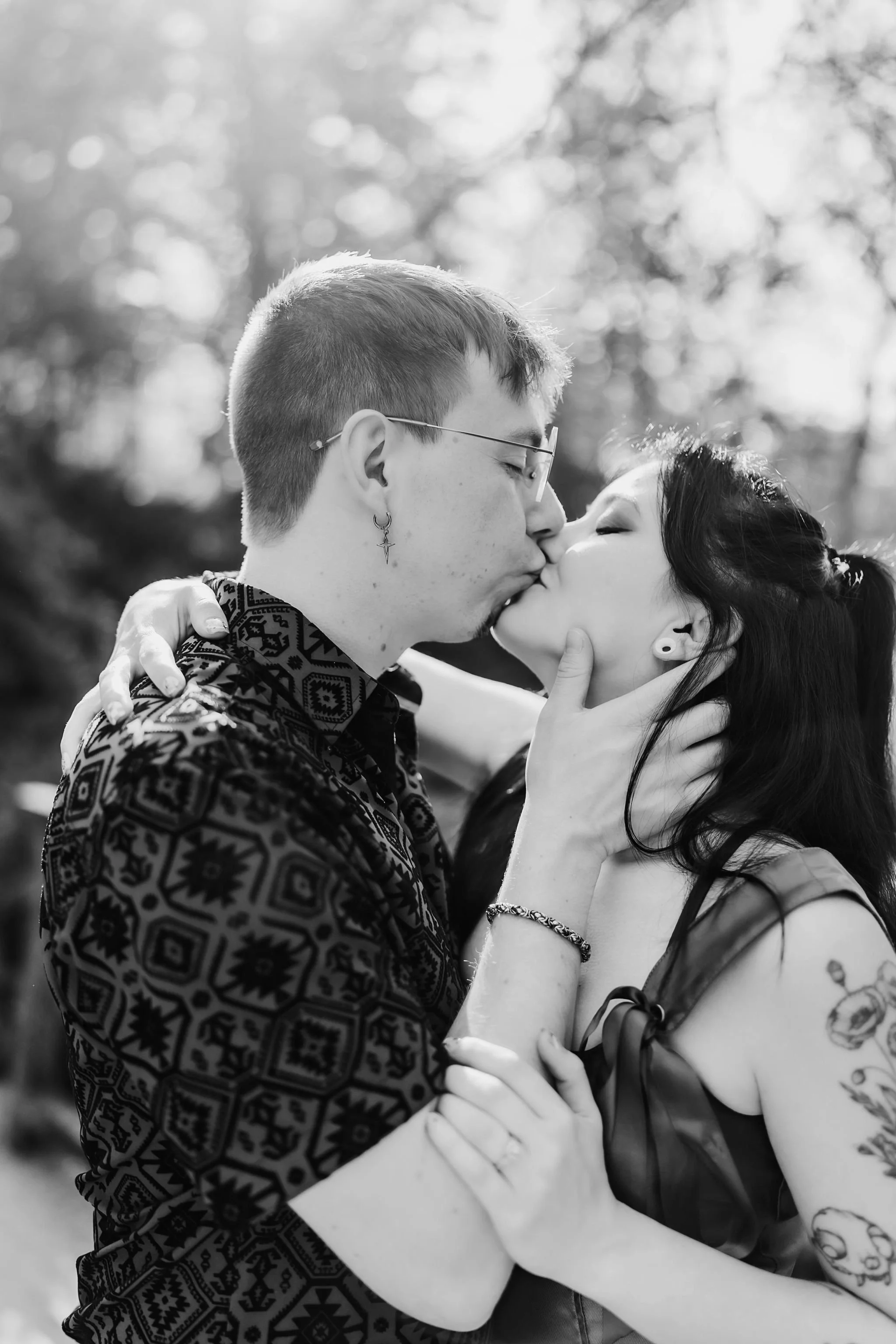 A black and white image of a couple sharing a kiss during their engagement photo shoot