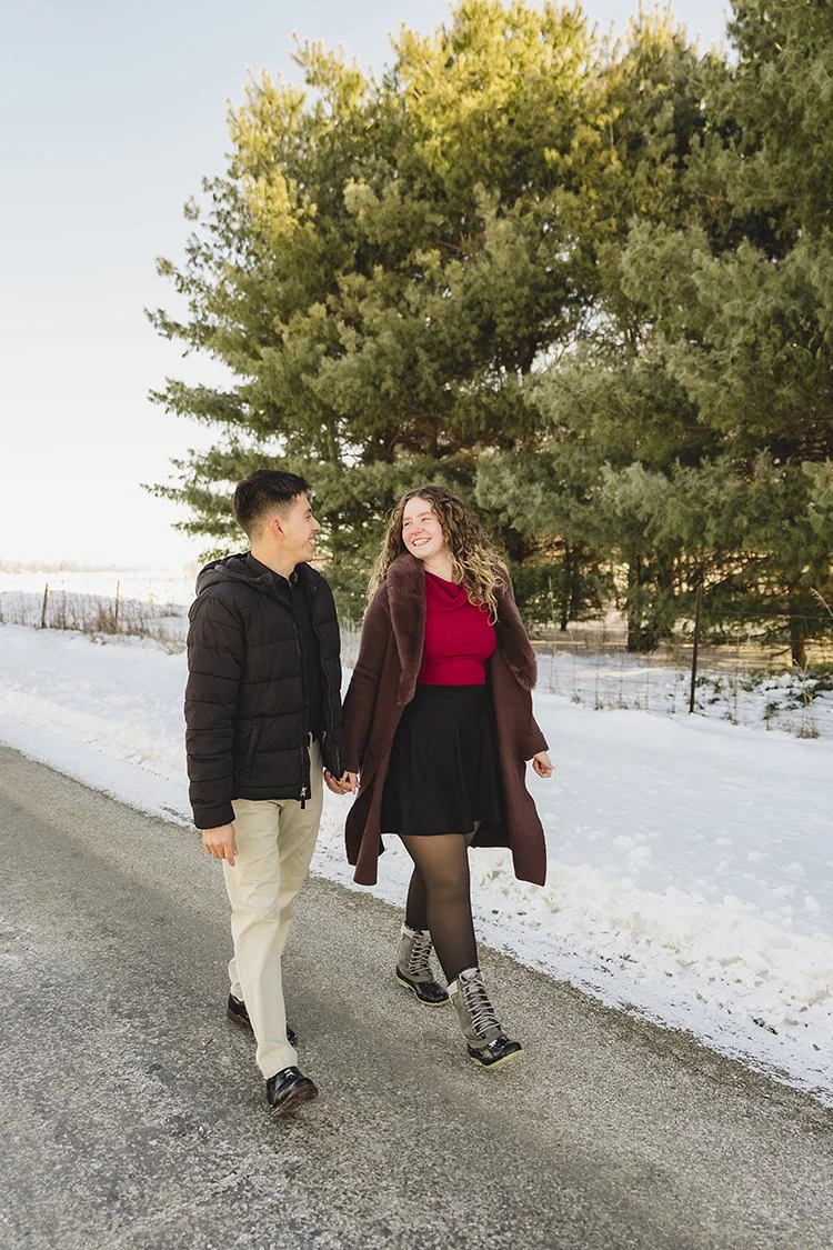 Couple walking hand in hand through a snowy outdoor setting in Indiana on a winter day.