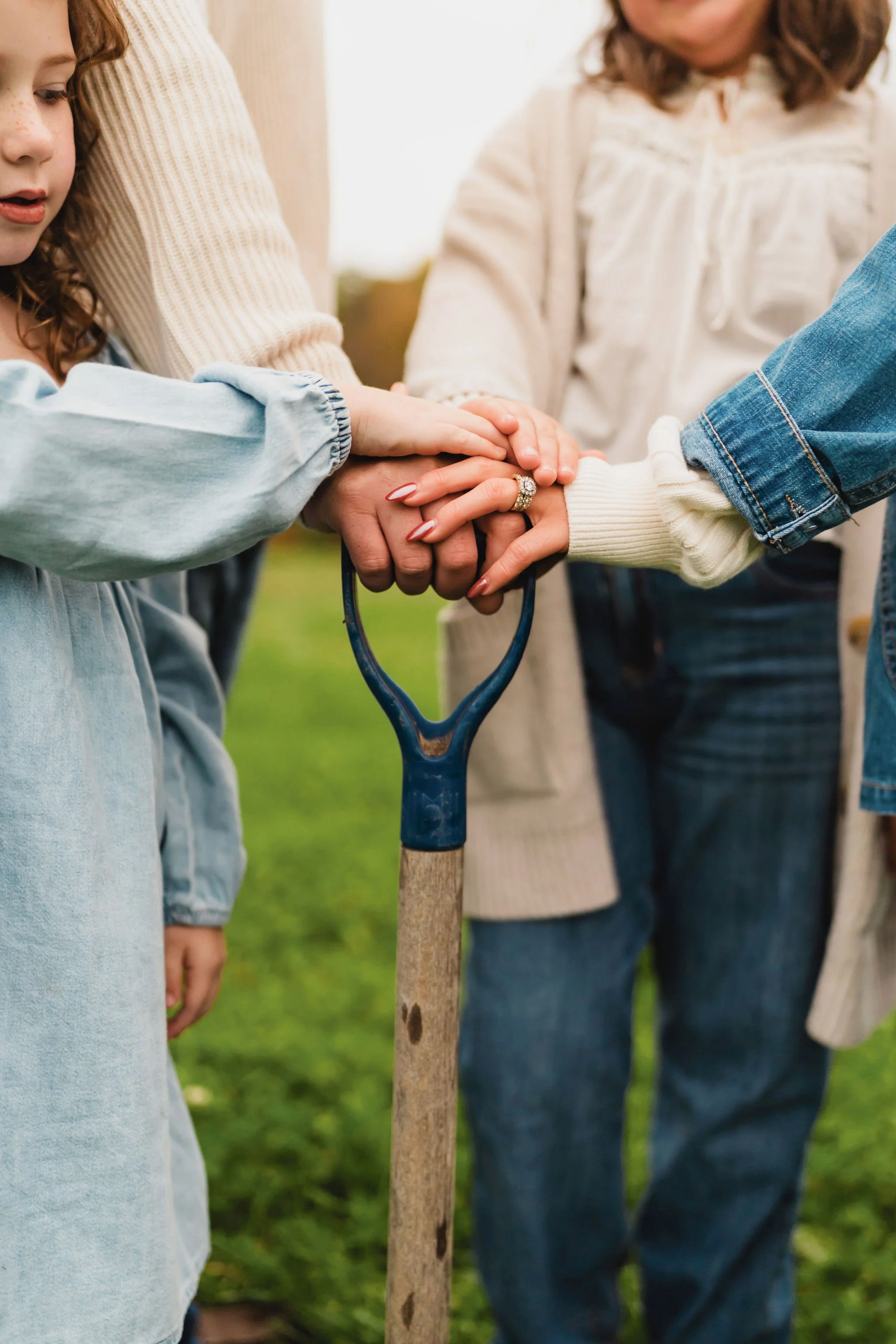 Close-up of family hands gathered together around a shovel on their future homesite.