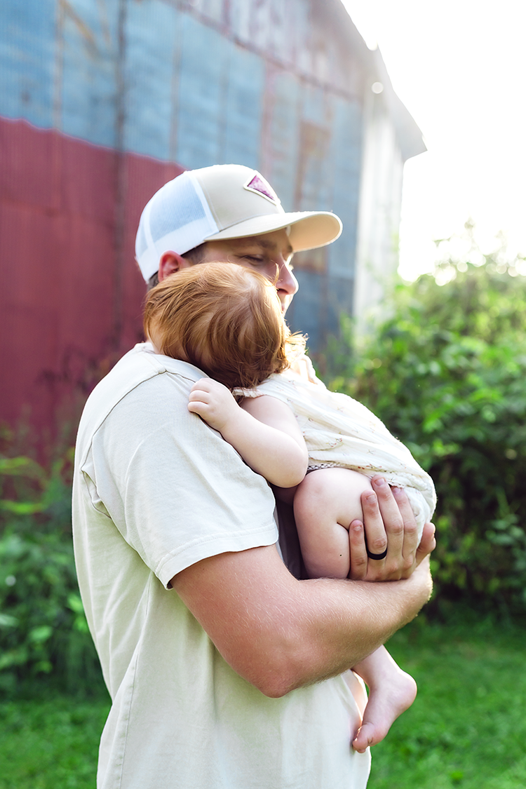 A father holds his one-year-old daughter and hugs her during their photo session.