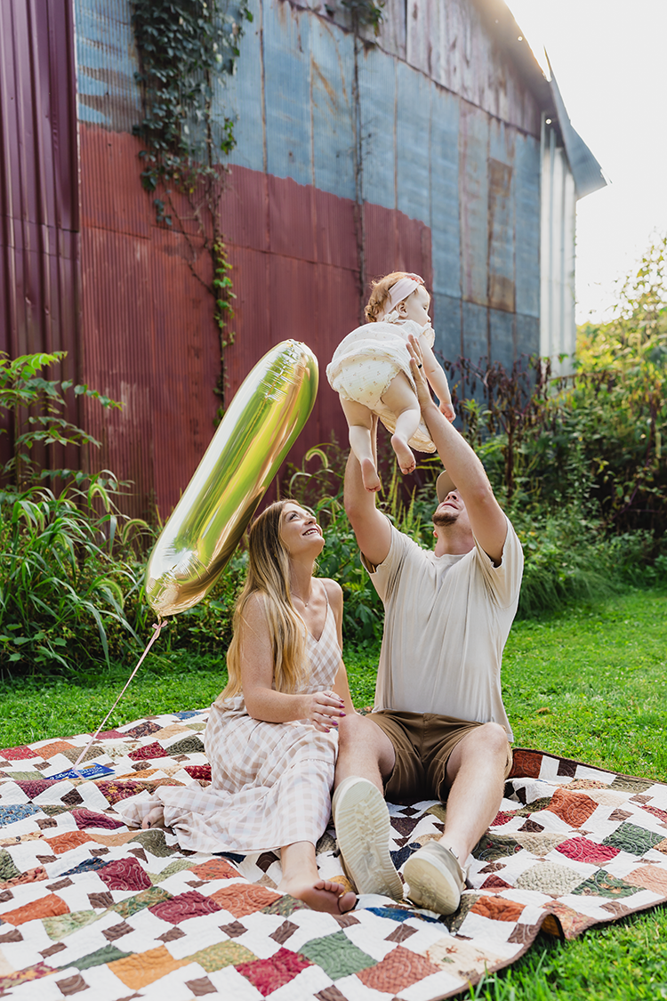 Dad holding his baby girl in the air while mom watches and smiles during their family session.