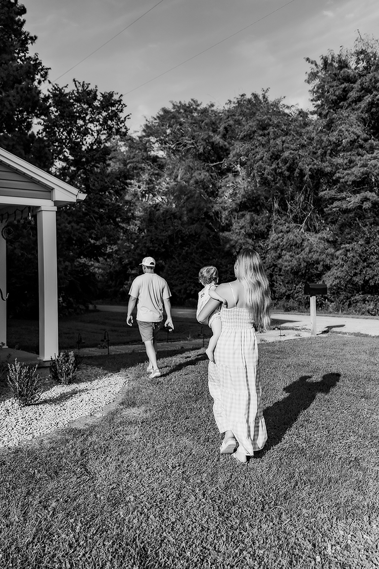 A candid image of a young family walking towards their home during their lifestyle photo session.