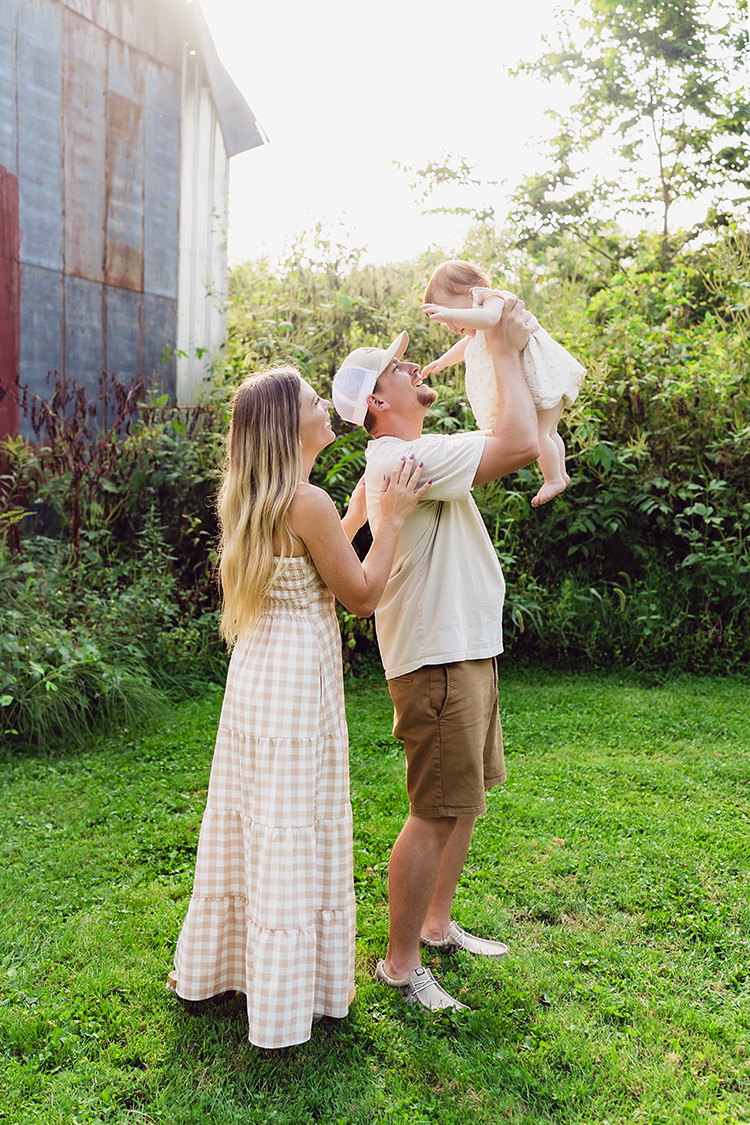Mom and dad lifting their baby girl into the air during her first birthday family photo session.