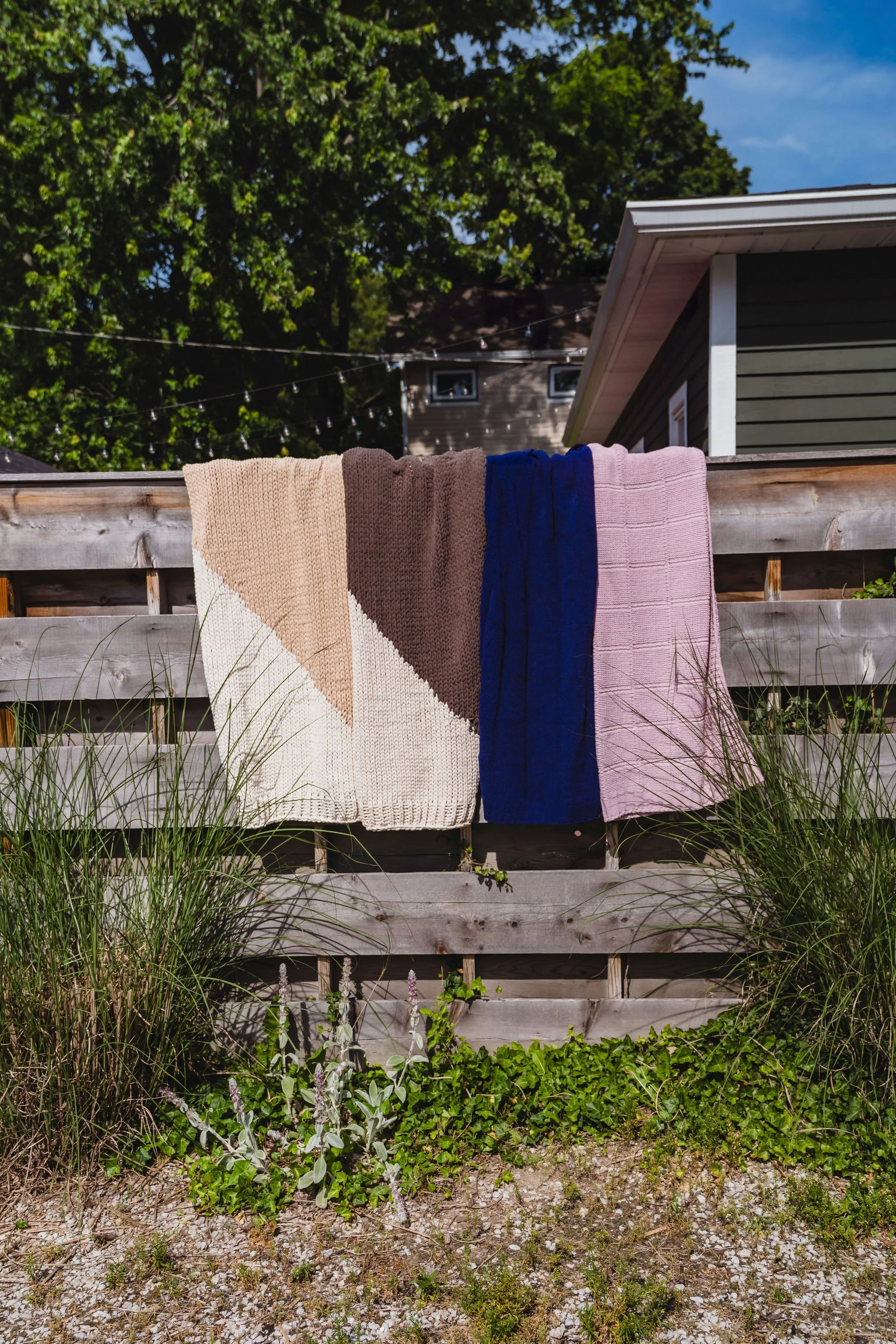 Soft neutral knit blankets draped over fence during lifestyle product photography session