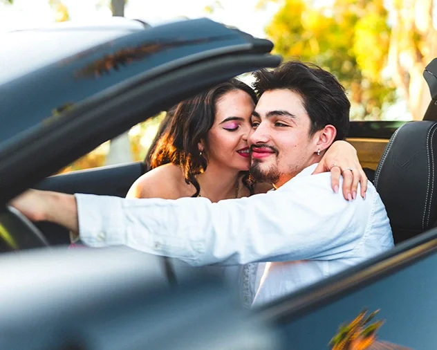 Couples photography session in Indiana with couple embracing in convertible surrounded by fall trees and autumn leaves