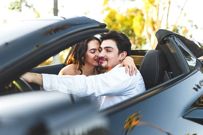 Couples photography session in Indiana with couple embracing in convertible surrounded by fall trees and autumn leaves