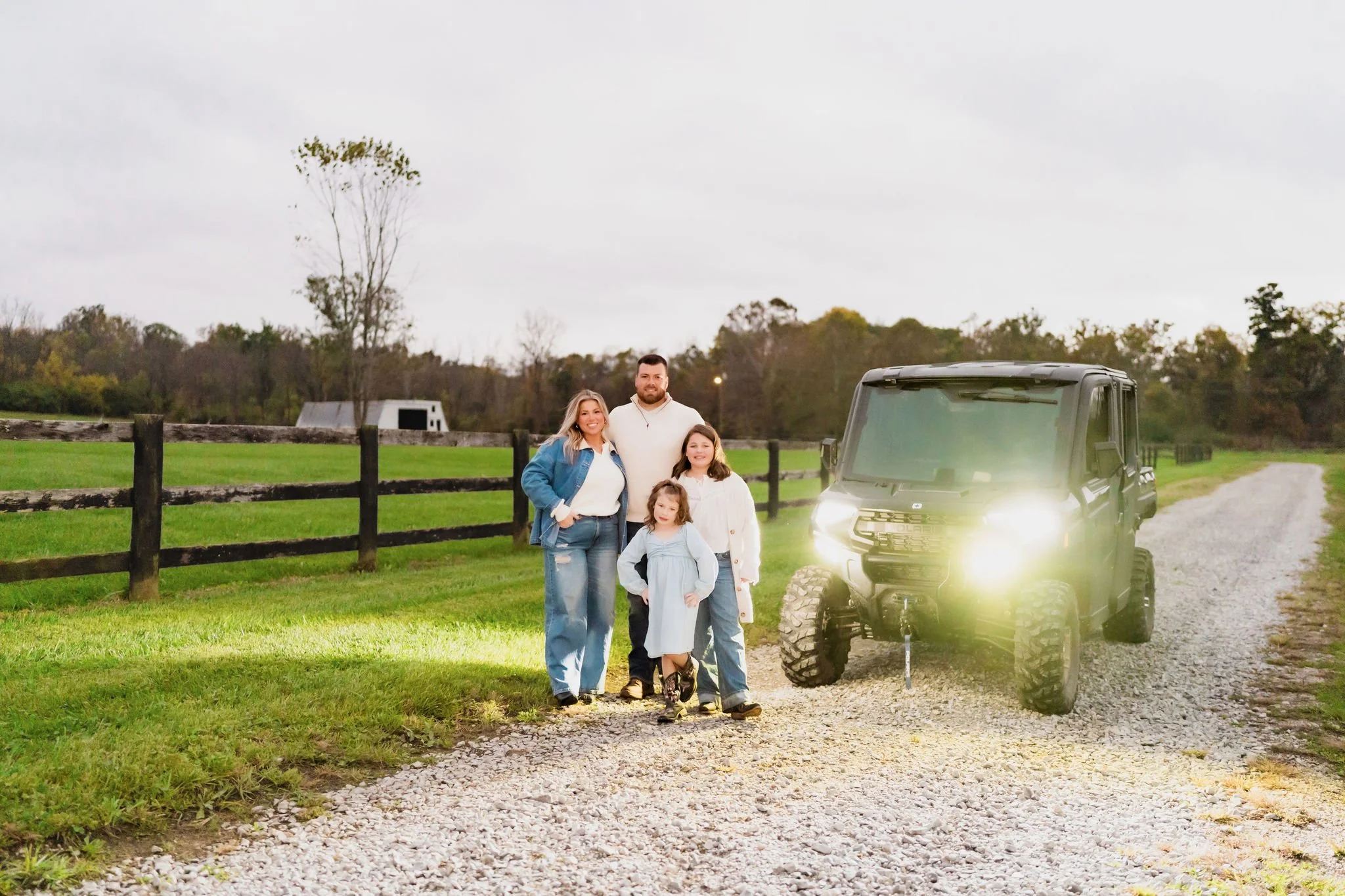 Family standing on the land that will become their home, photographed in autumn.