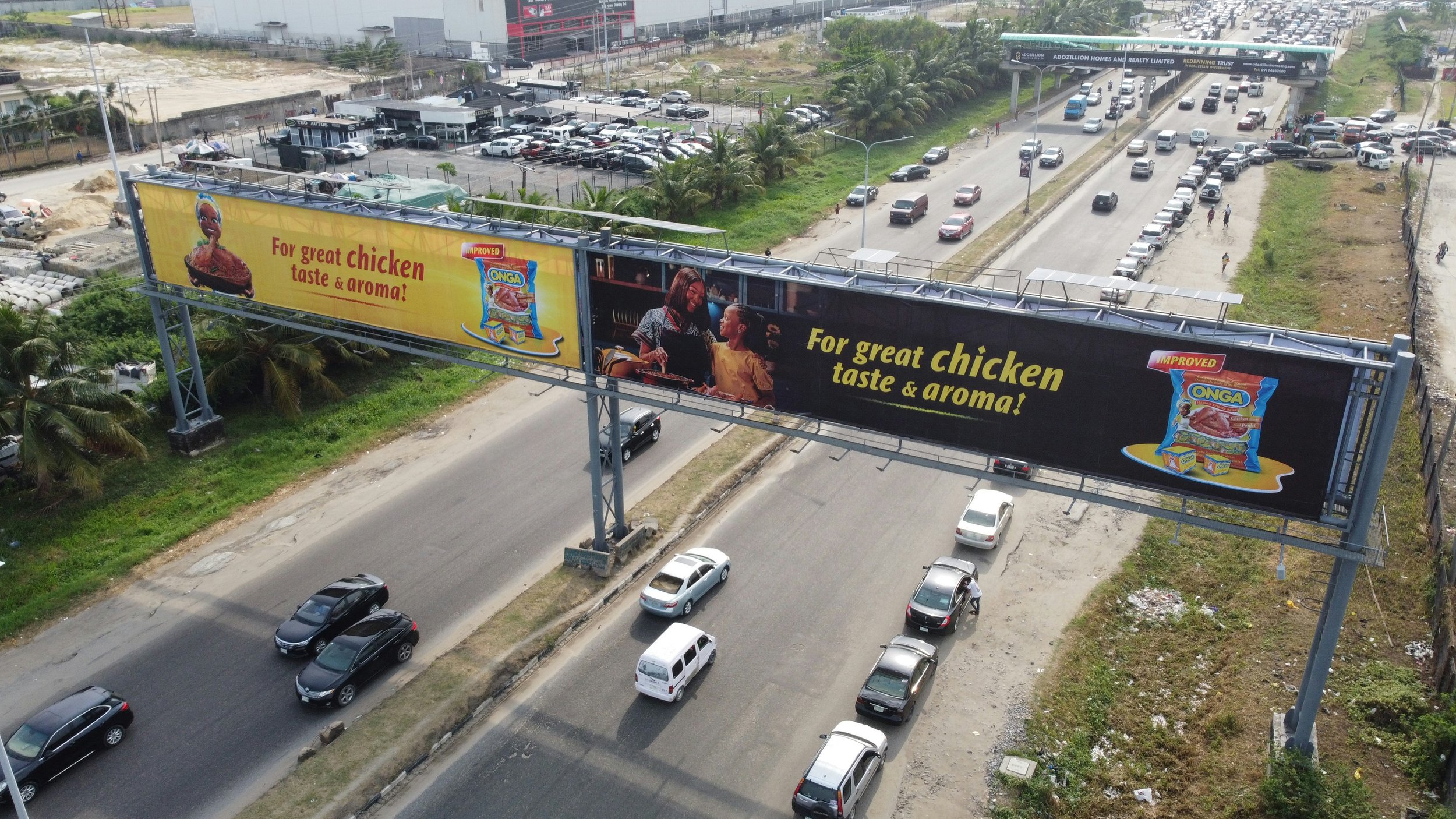Billboard advertisement for chicken flavor snacks featuring a pack of Onga brand with a plate of cooked chicken, and a picture of two women smiling, with the text 'For great chicken taste & aroma!'