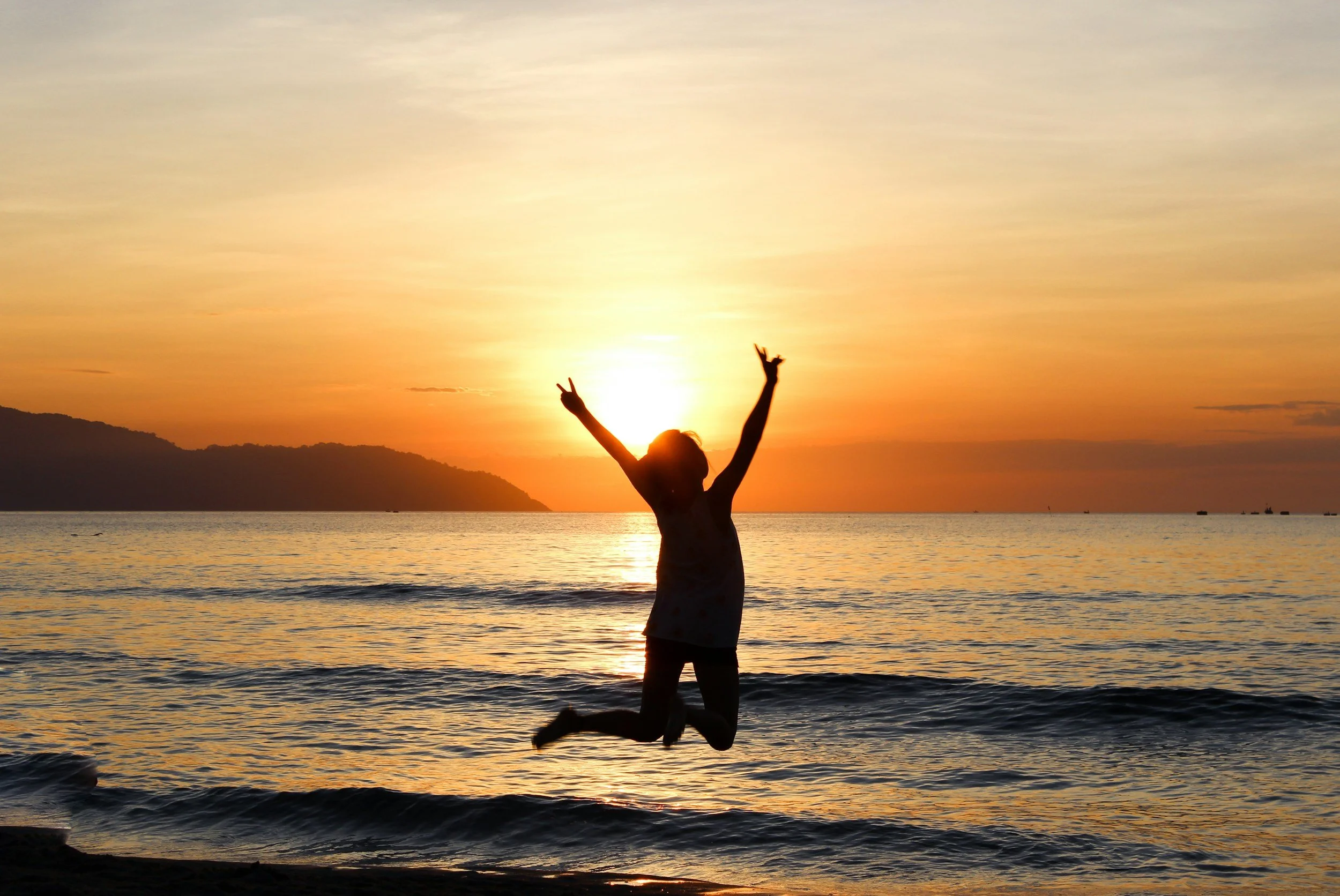 Lady leaping into air at sunset