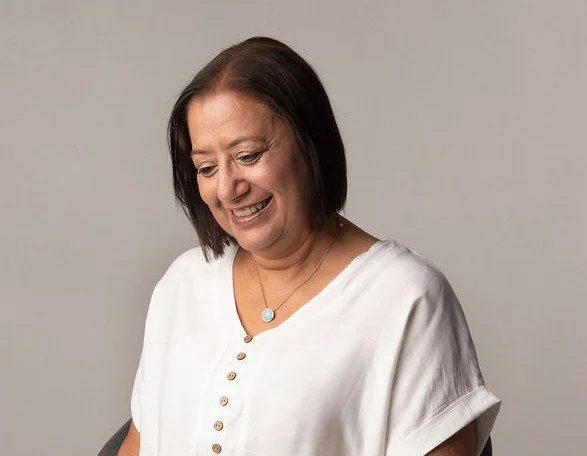 Jackie Mandeir smiling and looking down, wearing a white top.