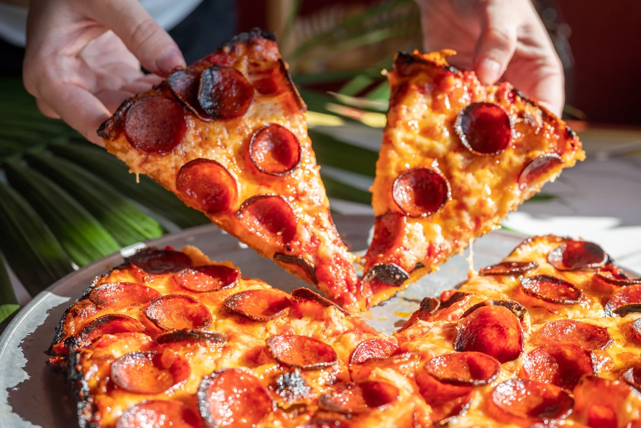 Pepperoni pizza slices being pulled