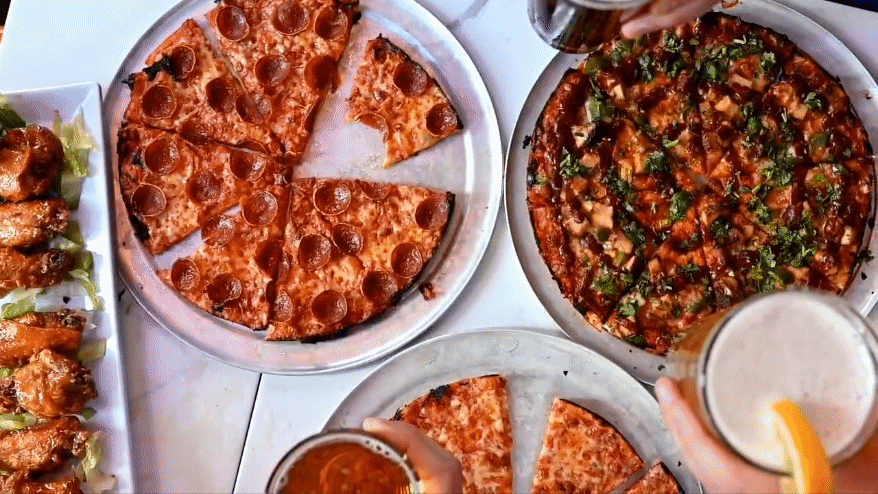 Assorted pizzas and wings overhead cheersing