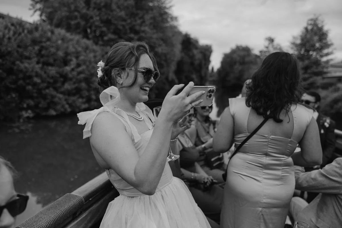 wedding guest taking a photo on a phone during a drinks reception on a boat in bristol