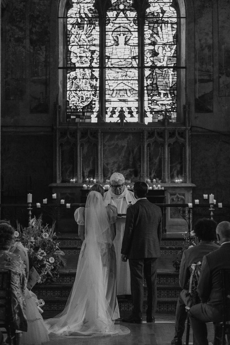 bride and groom facing forwards towards the priest at the mount without
