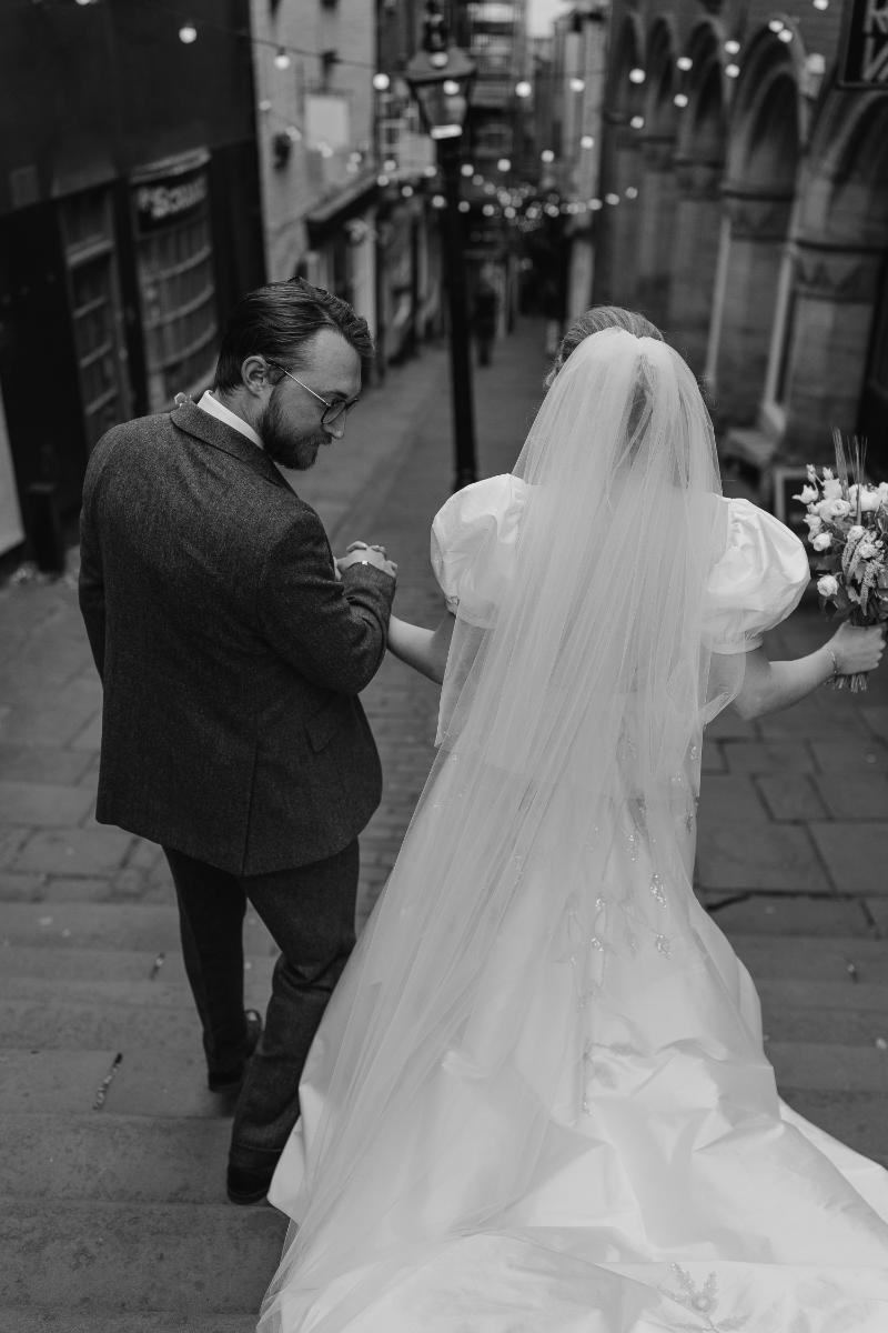 candid back shot of bride and groom walking