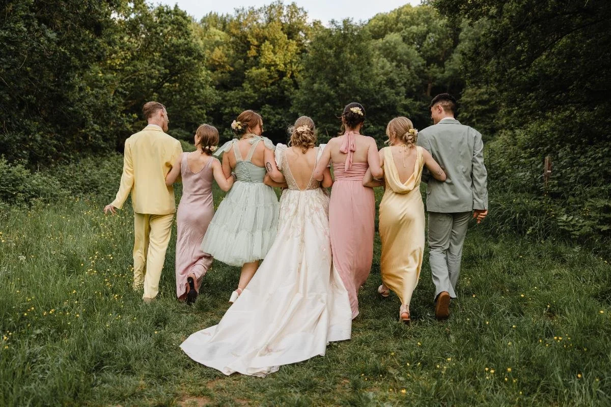 bride and bridal party in mismatched outfits walking away