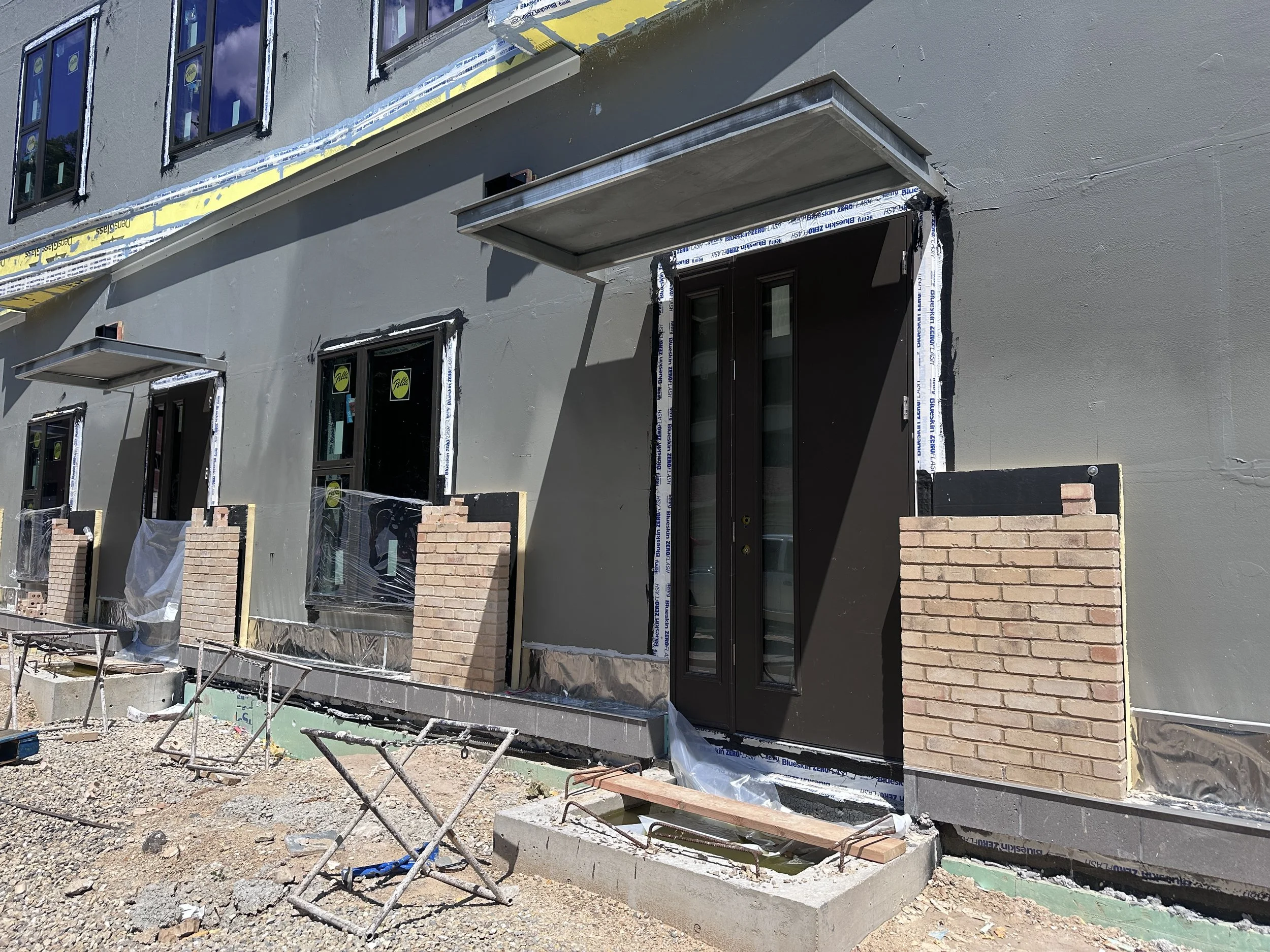 06.22.2026 - Luna (B1) apartment patio doors and facade brick are being installed.