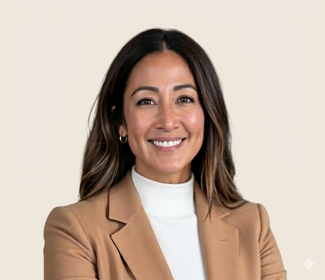 A professional woman smiling with shoulder-length dark hair, wearing a beige blazer over a white turtleneck, against a light beige background.