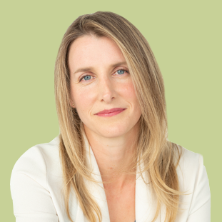 Portrait of a woman with straight blonde hair and blue eyes, wearing a white top, against a green background.