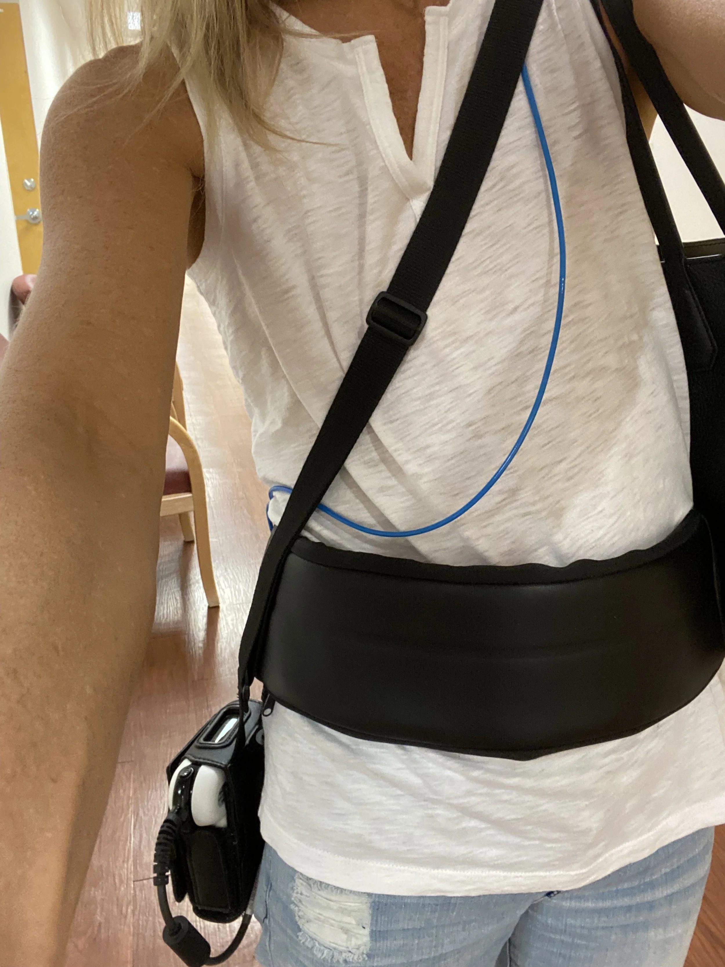 A picture of Julie wearing a white shirt, jeans, and a black test kit wrapped around her waste and body. She is wearing this to track the PillCam as it goes through her body for an endoscopy test.