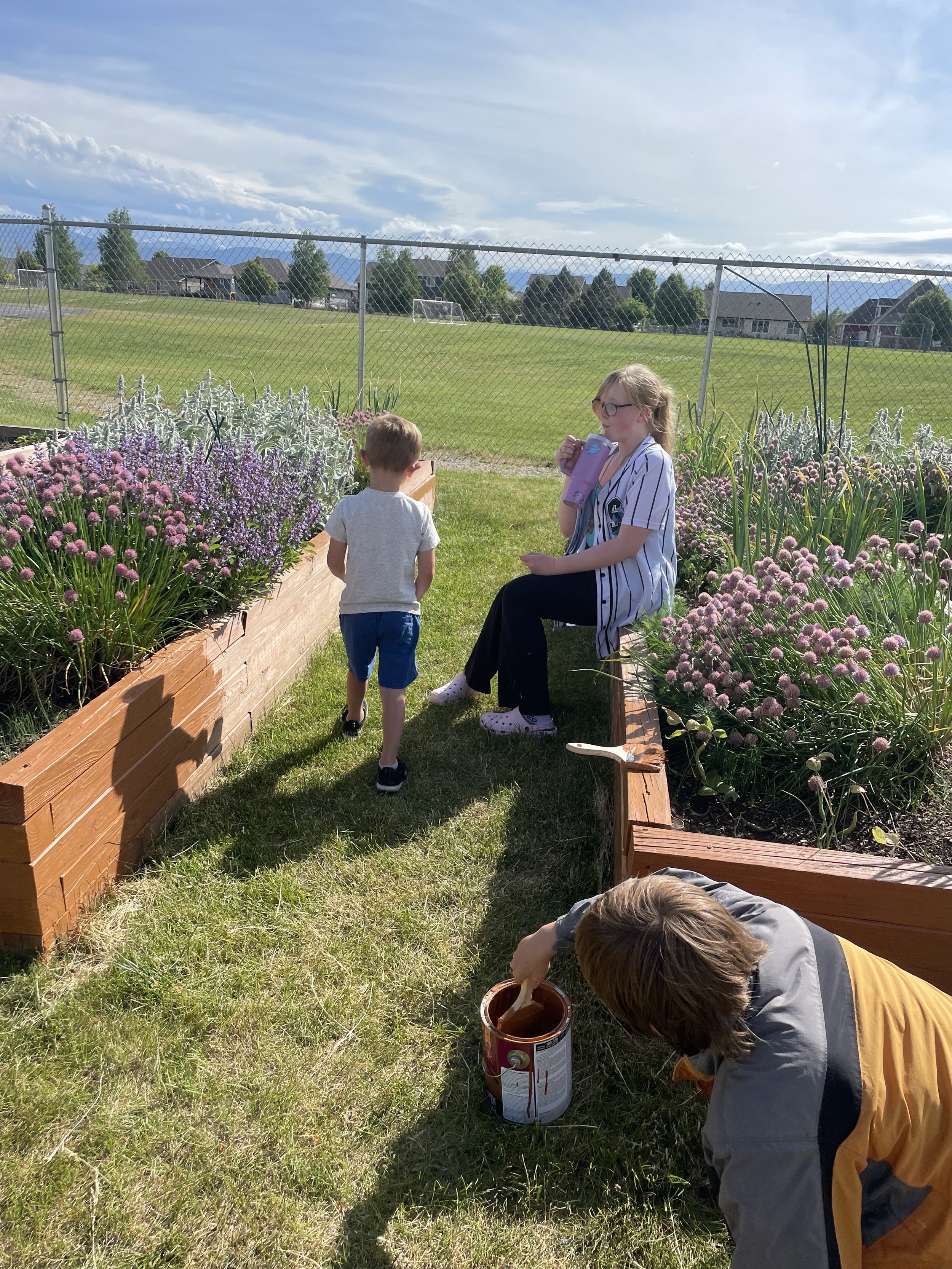 Students taking a break while others paint the garden bed.