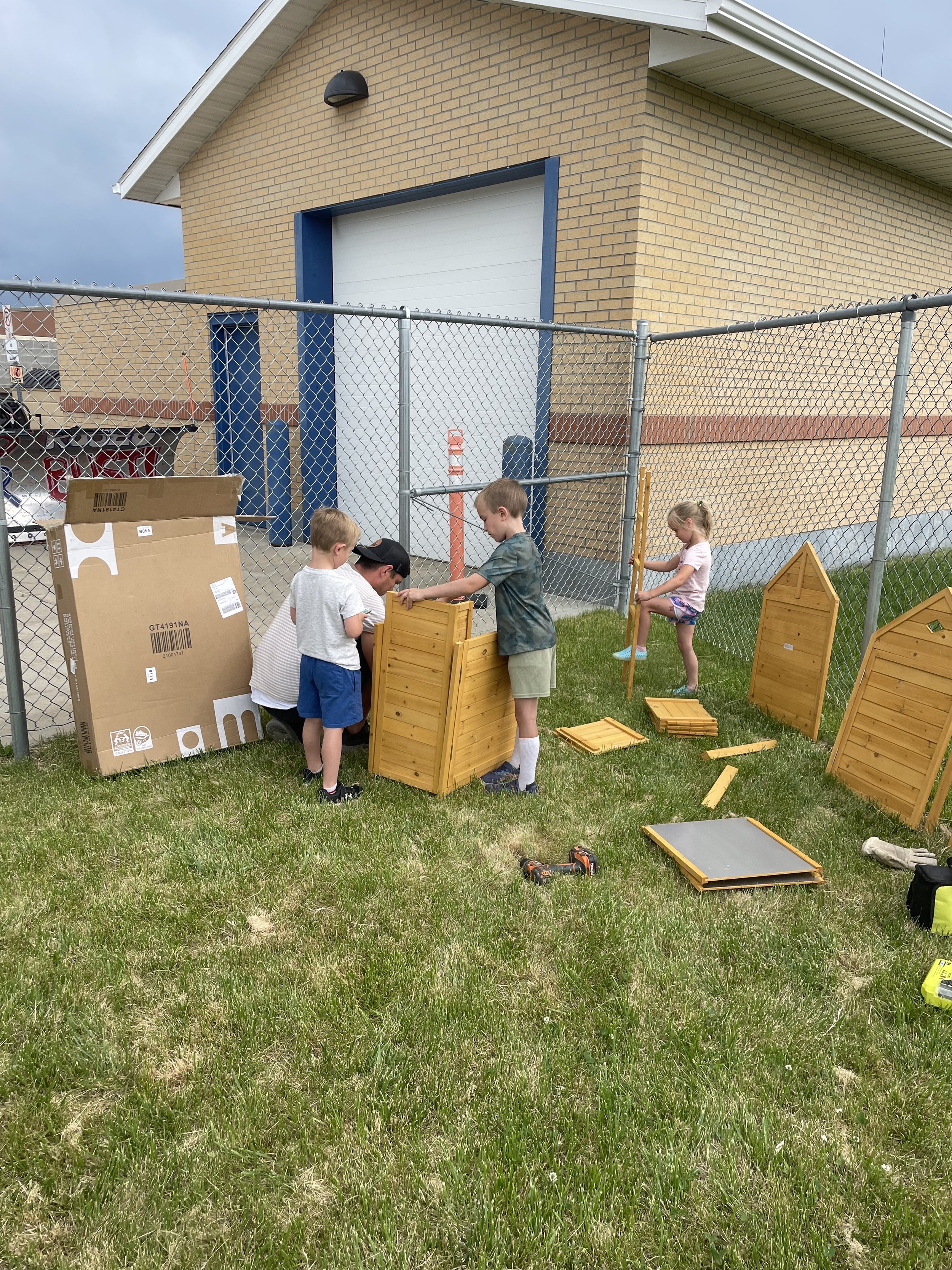 Children helping volunteer to assemble the Garden Shed.