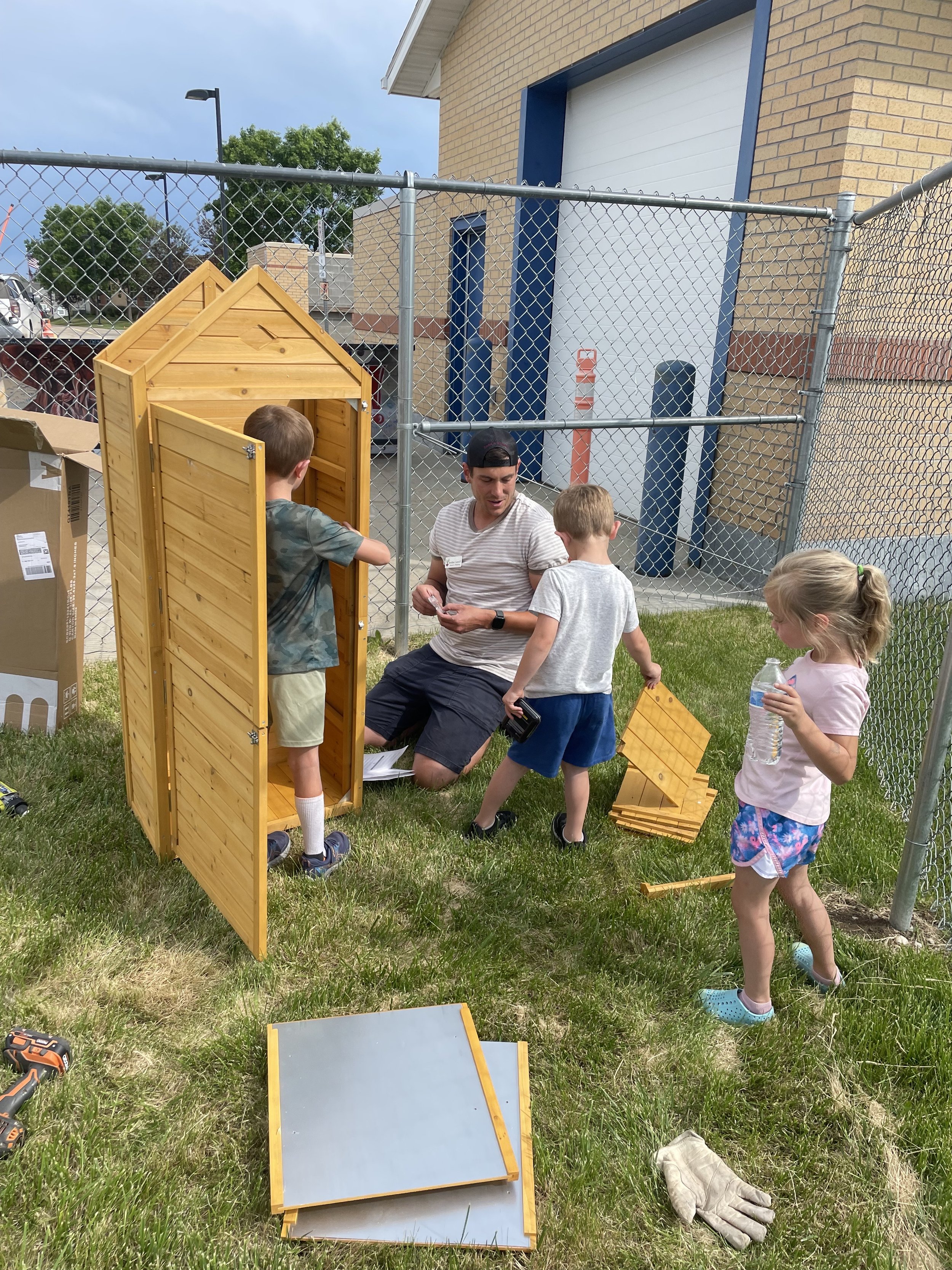 Children assisting with the assembly of a garden shed.