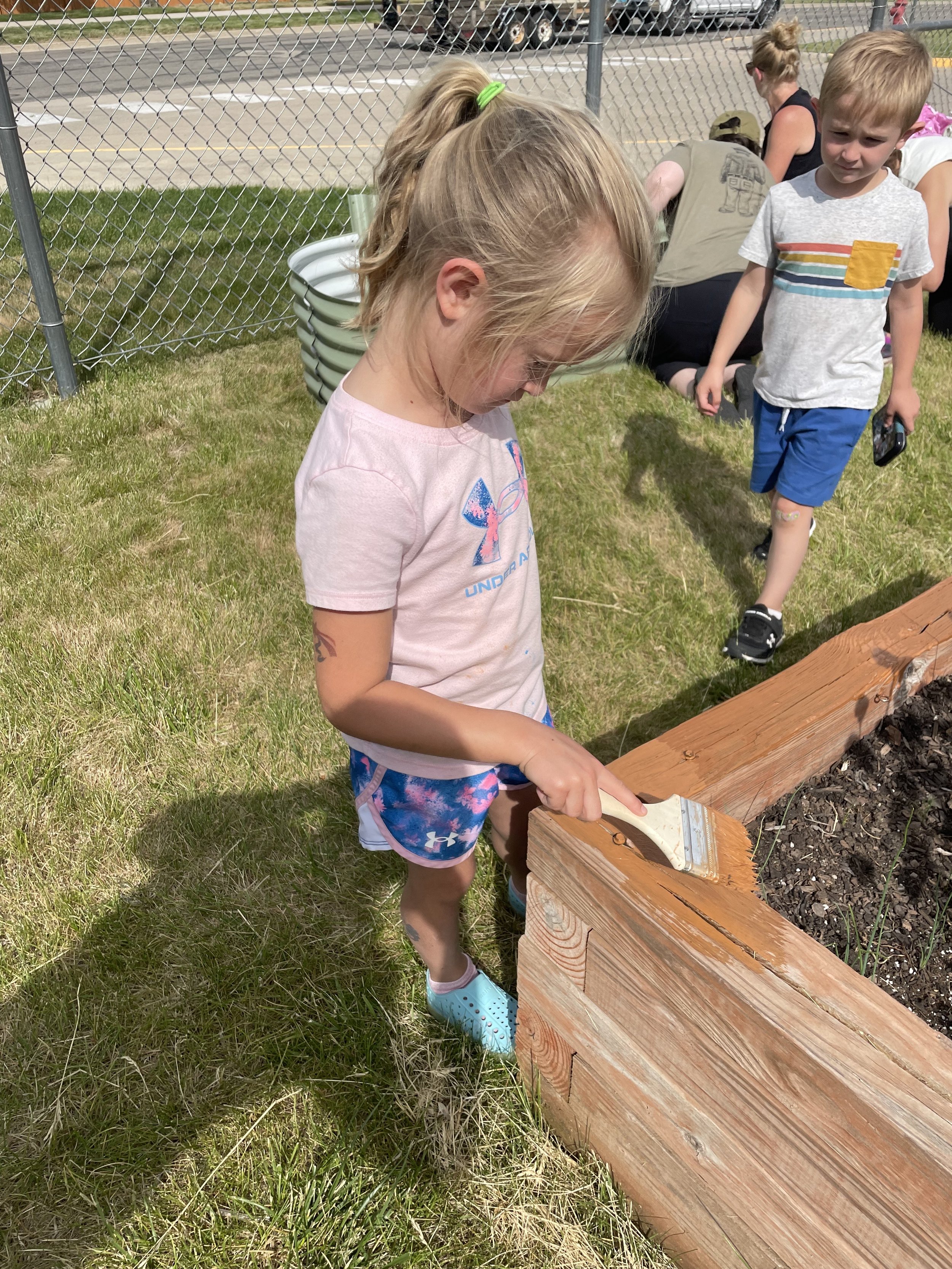 A student painting the garden bed.