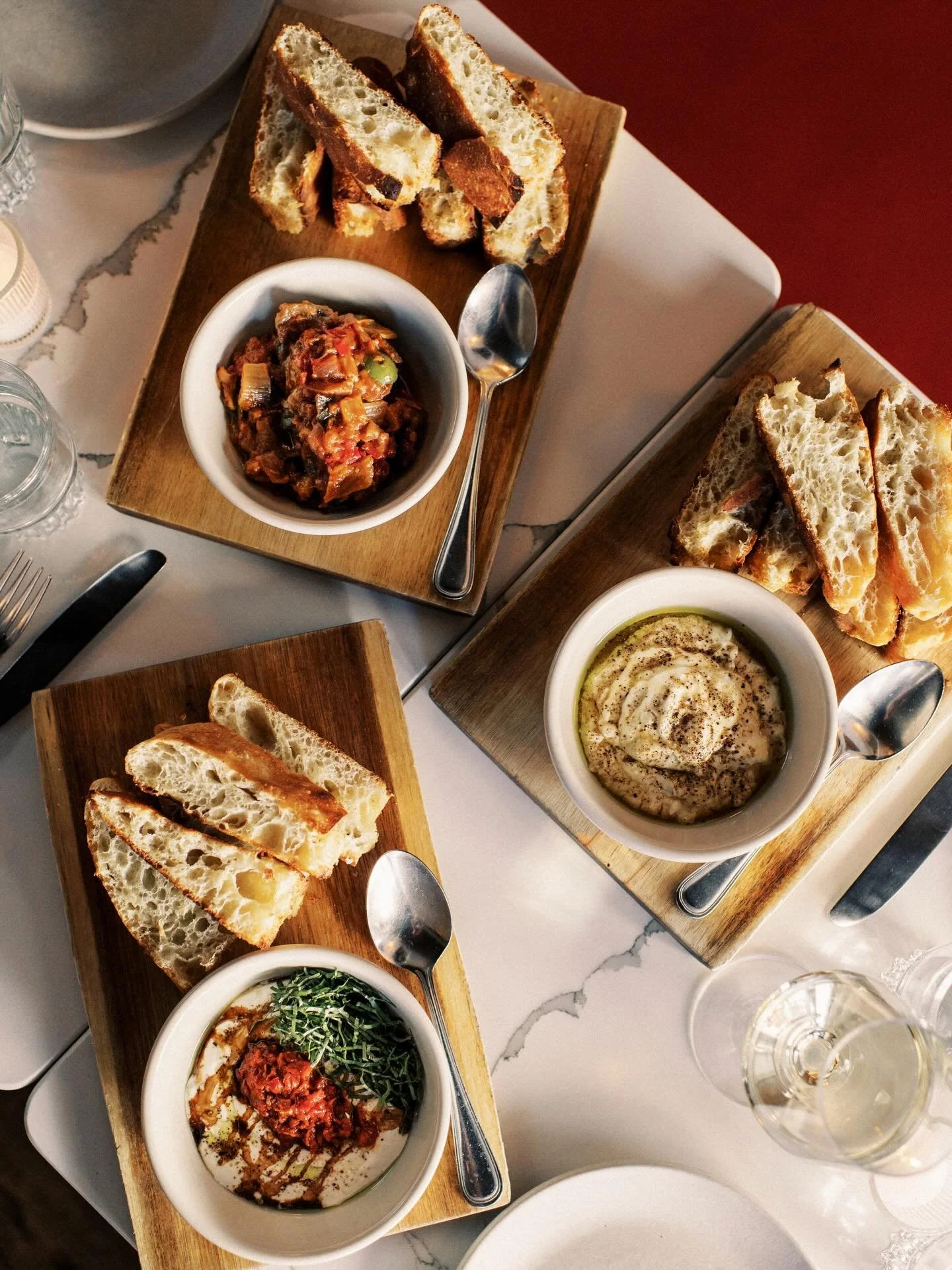 Craving our signature Pizza Bianca? 
Fresh from the oven for dine-in or takeout 🤌🏼✨
 + Stracciatella, tomato relish, aged balsamic
 + Lemon whipped ricotta, hot honey
 + Eggplant caponata

📸 @ggabriella 
.
.
.
.
[ID: Tabletop scene featuring pizza