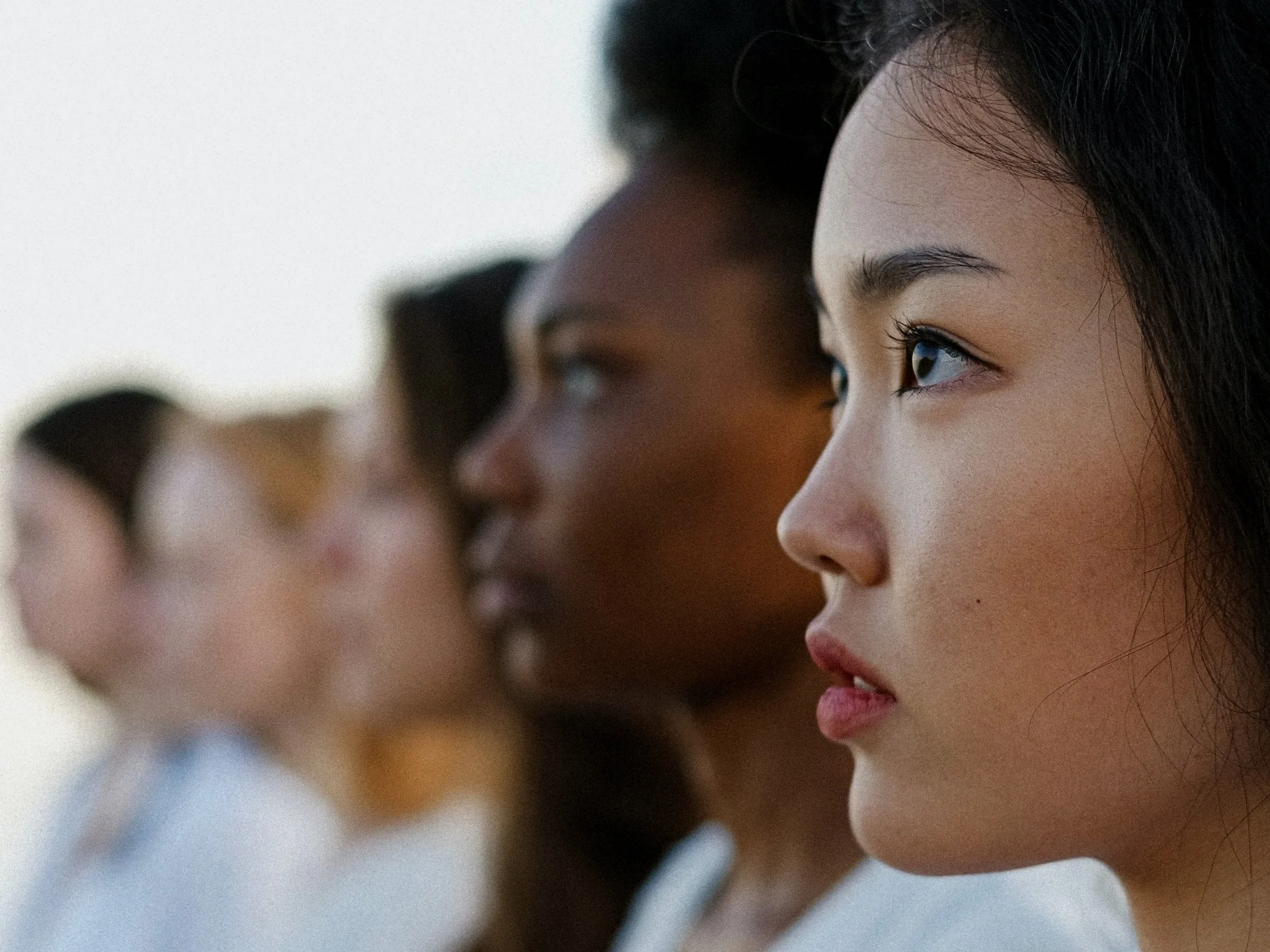 A line of feminine faces of various racial backgrounds. 