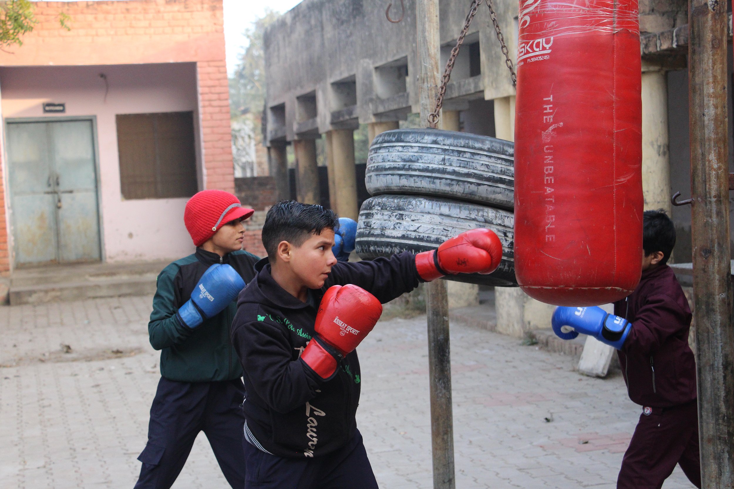  Anjali, 15, warms up on a punching bag before afternoon practice. Punching bags and old tires are used for training and are hung up in the courtyard of Harsola’s government school. | Photo by Emma Lovell 