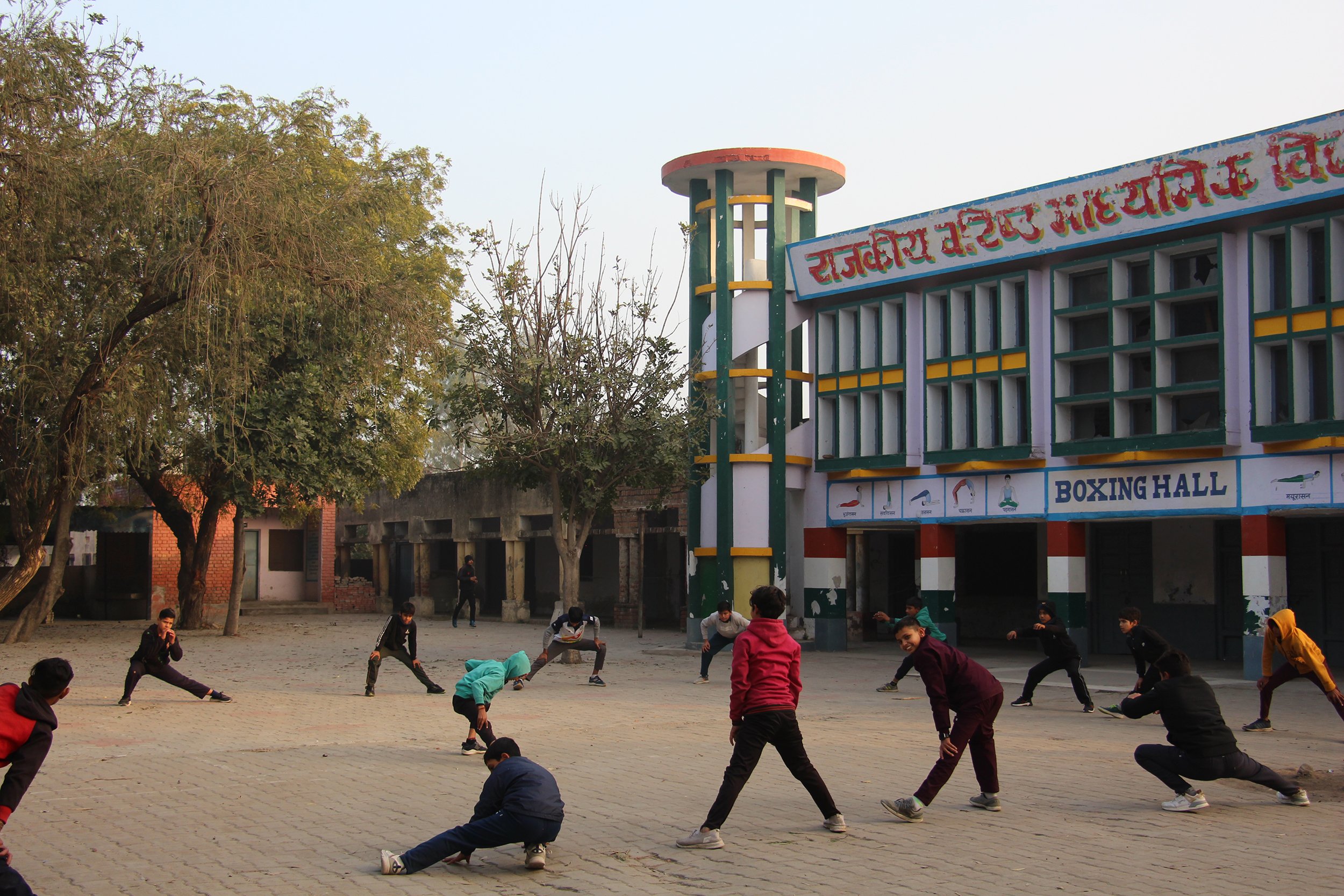  In the village of Harsola, school-aged boys and girls perform dynamic warmups to kick off their evening boxing practice. The school grounds are also home to many sports practices, including boxing, allowing students athletic instruction without trav