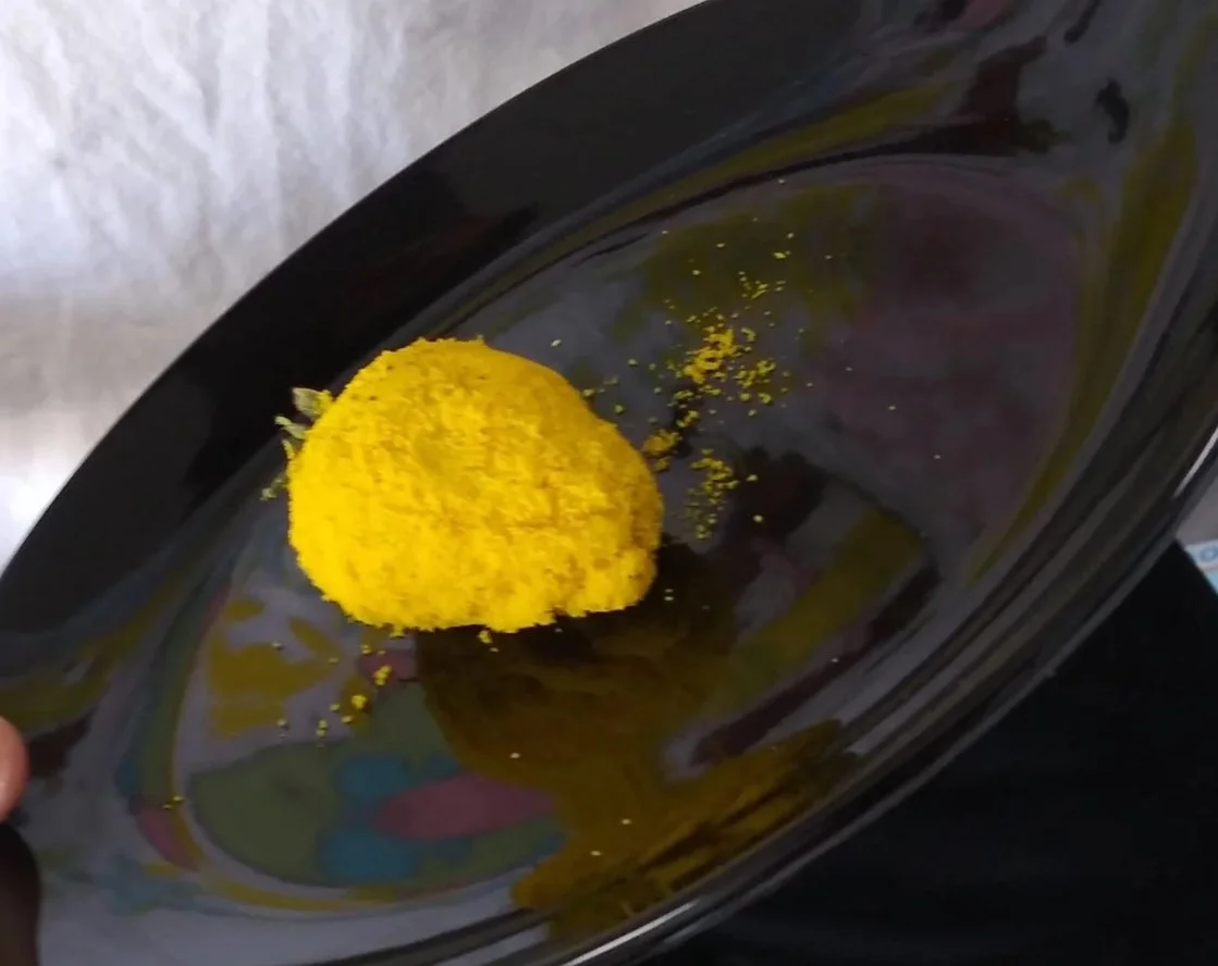 Strawberries coated with yellow crumbs in a plastic container on a red surface.