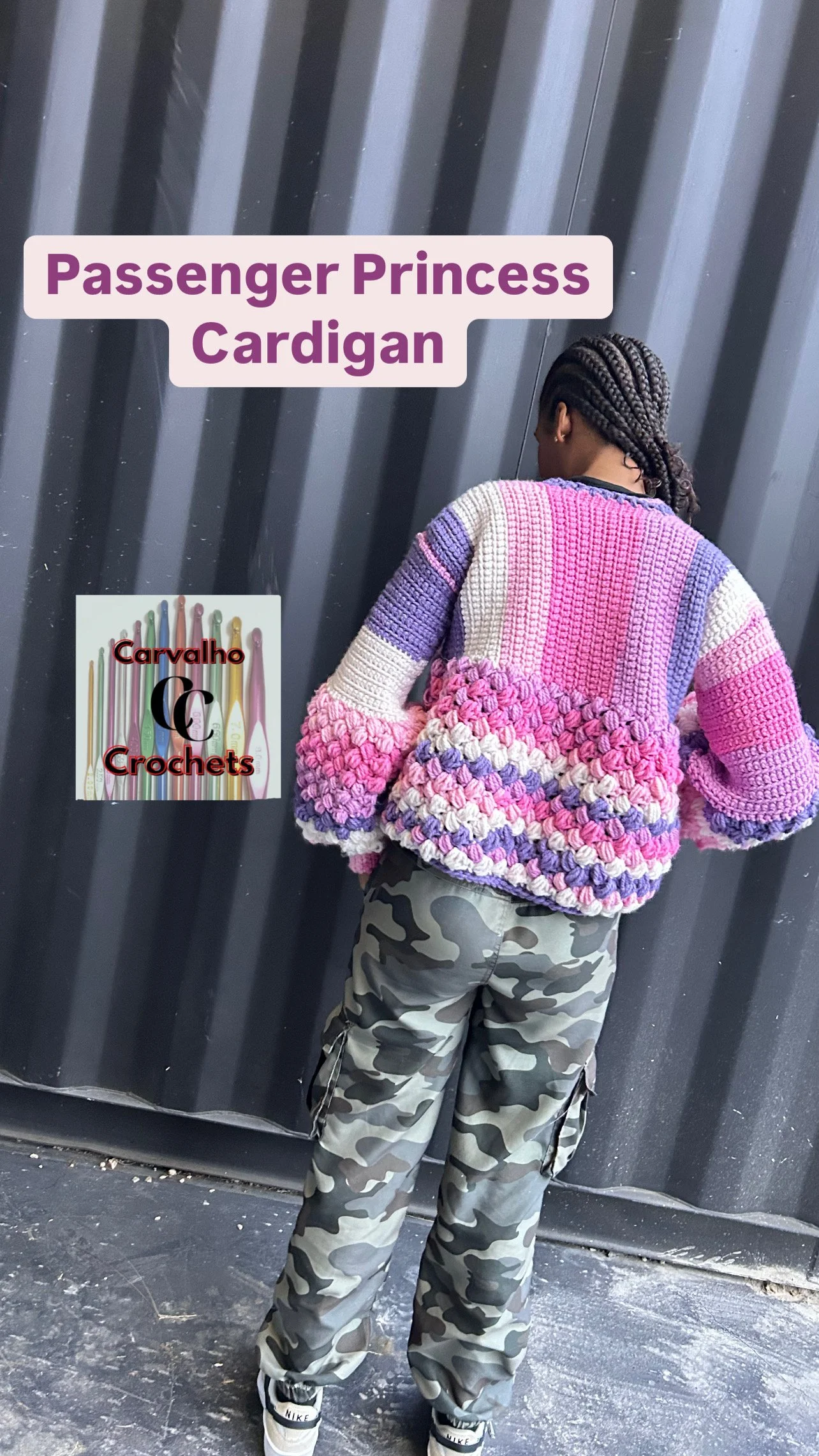 A person with braided hair wearing a pink and purple crocheted cardigan and camouflage pants, standing in front of a metal wall. Text overlay says "Passenger Princess Cardigan." A logo with colorful crochet hooks labeled "Carvalho Crochets" is also v