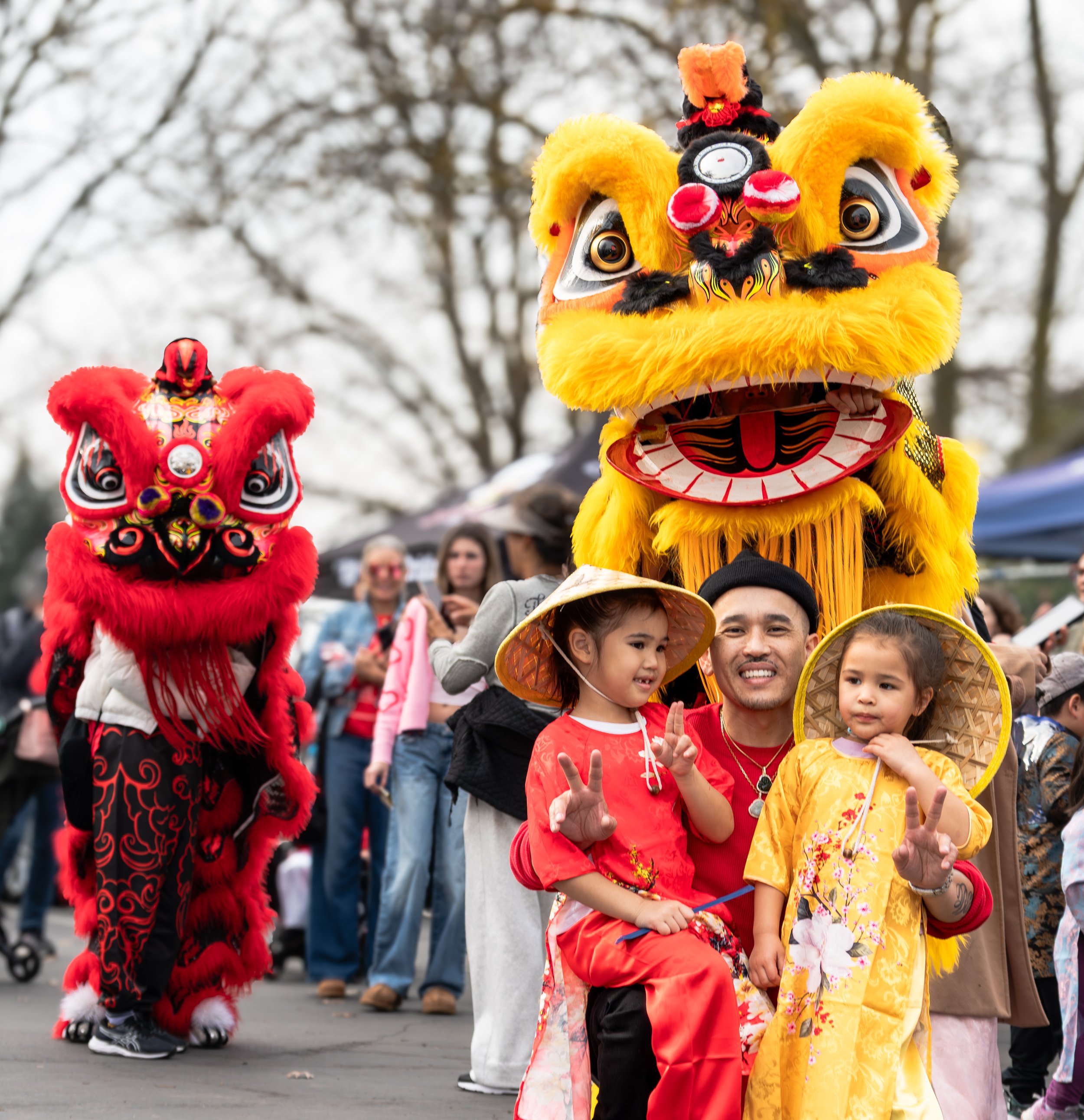 Lion dance performers with a father and two children in traditional dress at the 2026 Elk Grove Tết Festival