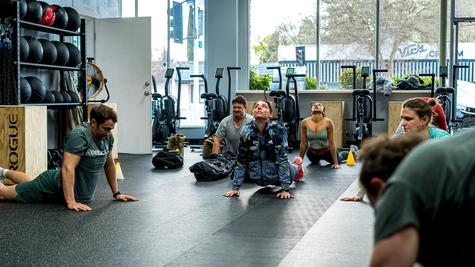 People in a gym with their bodies on the mat while pushing up their body from the floor with thier hands