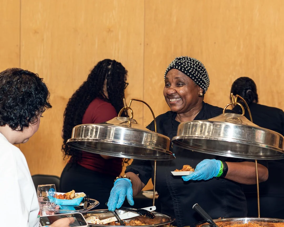 Lilian serving Nigerian cuisine to an attendee at Taste of Elk Grove event, smiling while interacting with guests