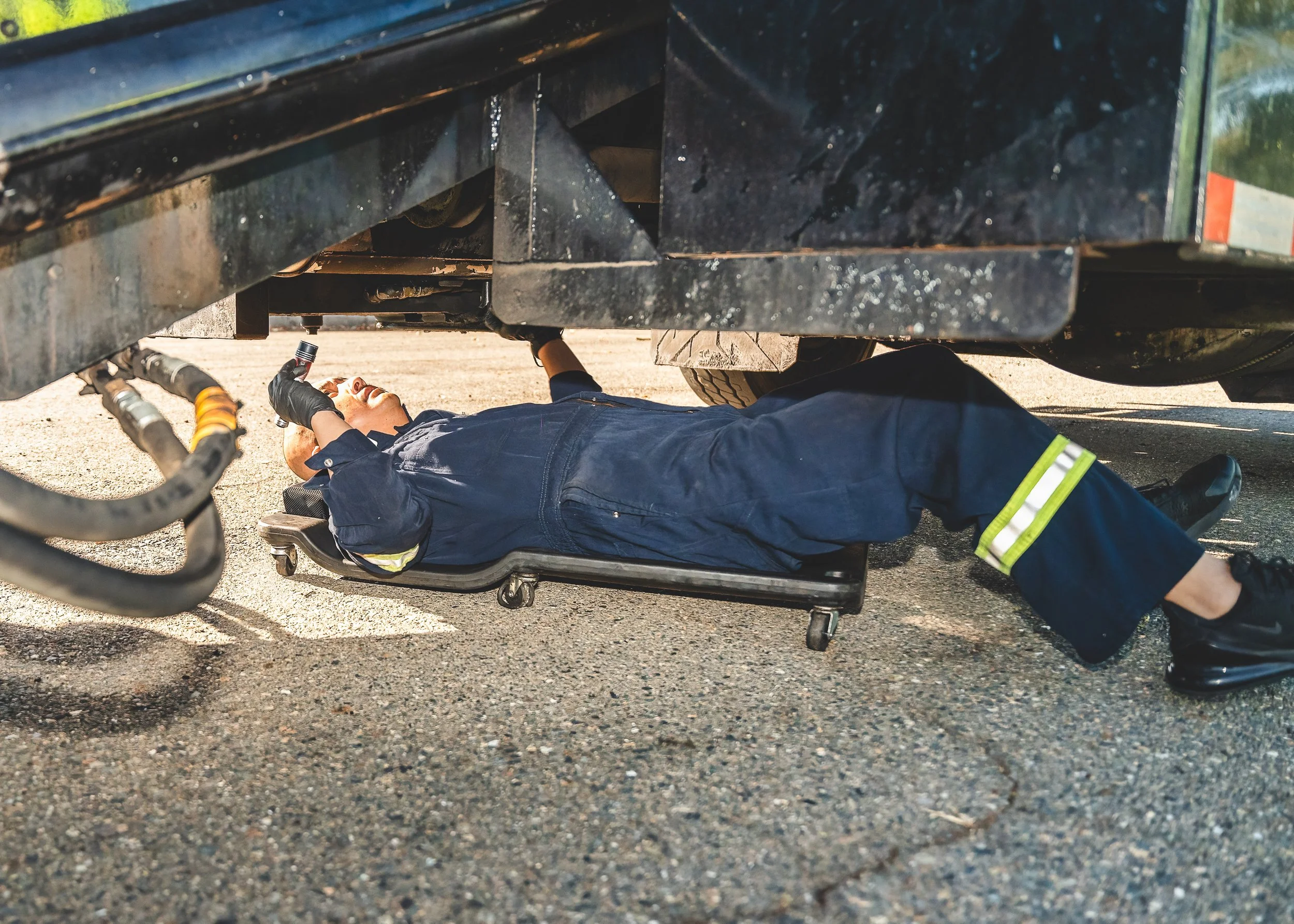 Technician performing maintenance underneath a service truck in a real work environment