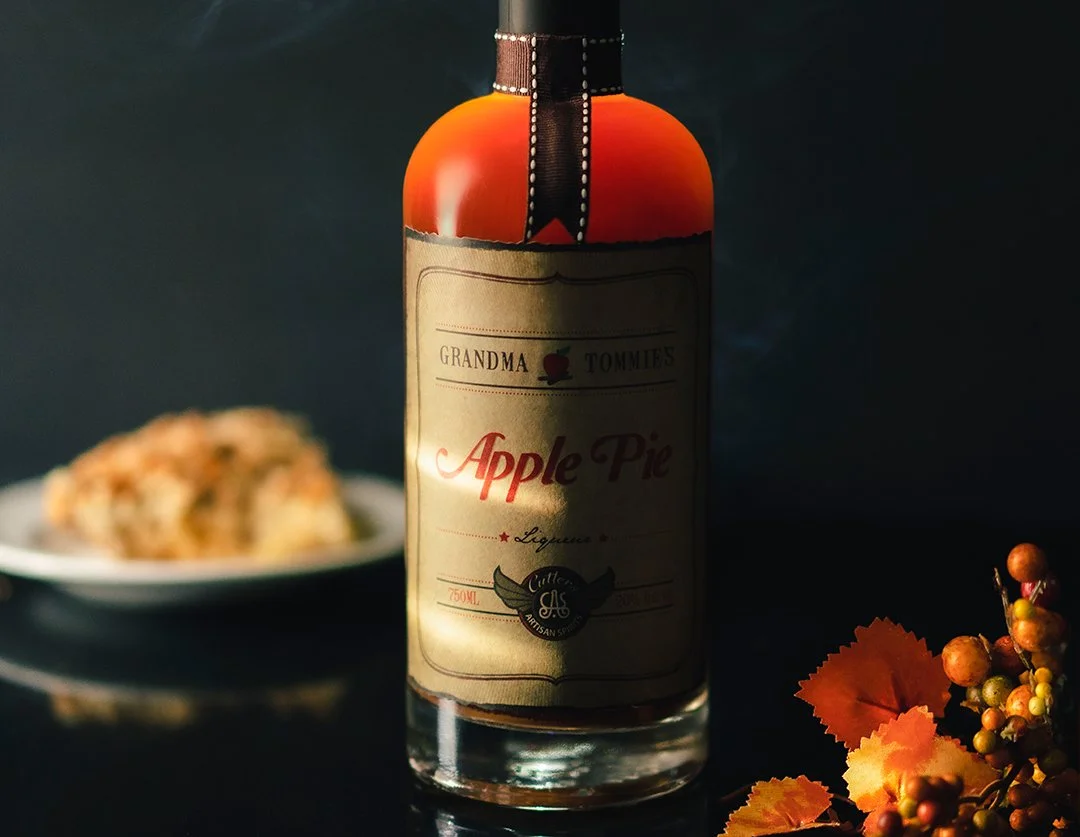 Warm-toned product photography of an apple pie liquor bottle with styled background elements