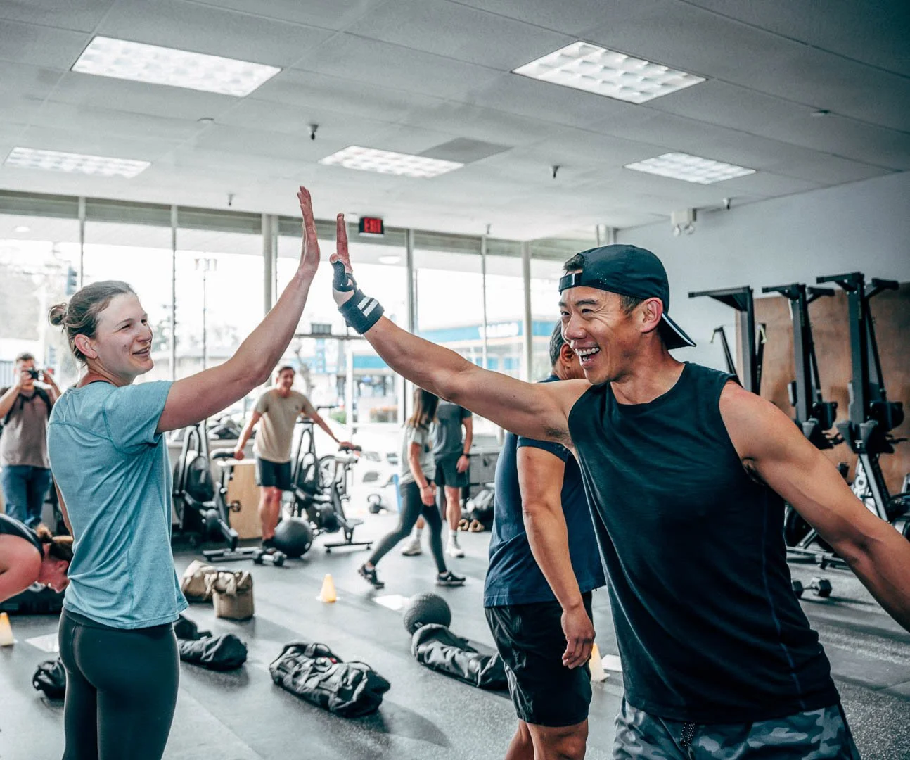 A man and a woman in a gym high-fiving each other after workout.
